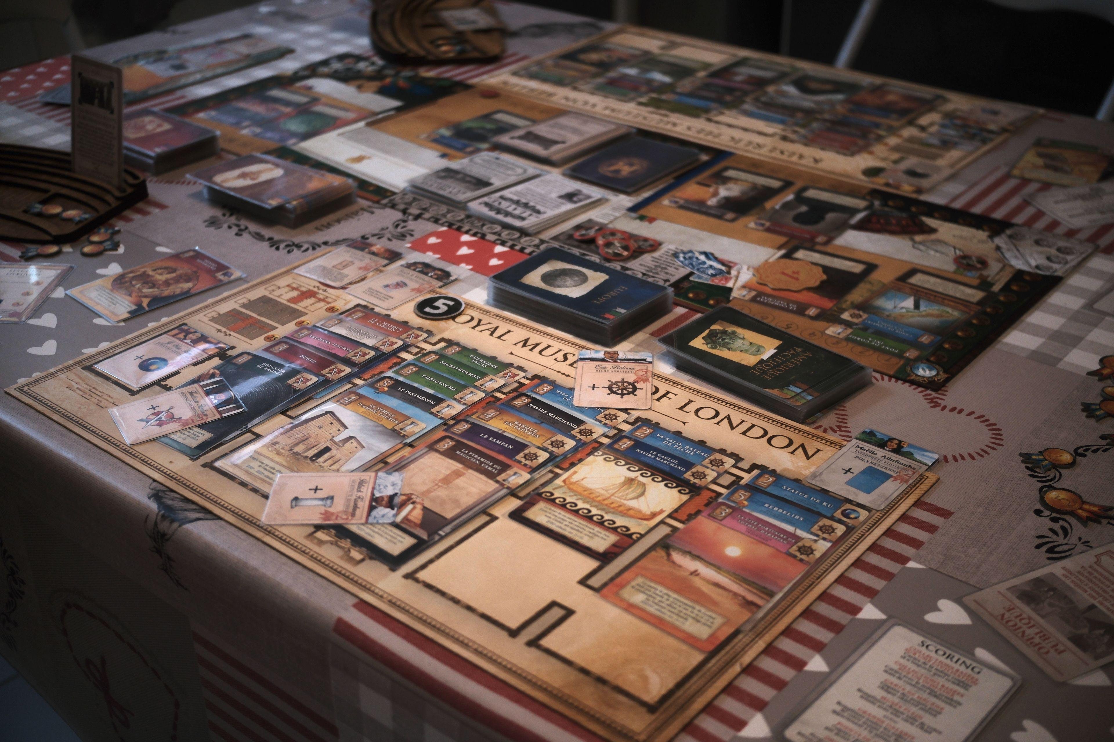 A table with a lot of cards, game boards, tokens…