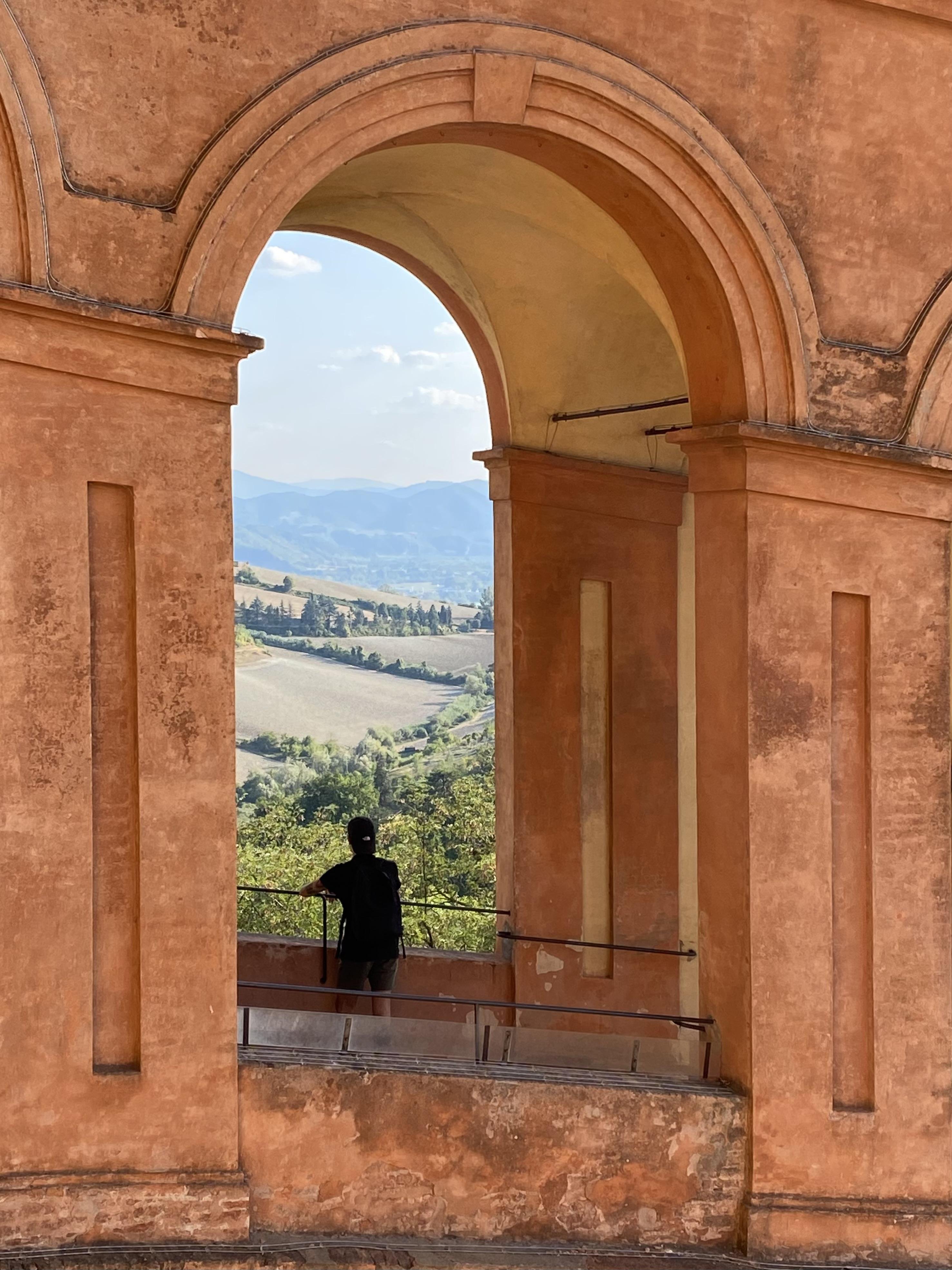 single arc of a portico showing a natural landscape with a person standing in the middle