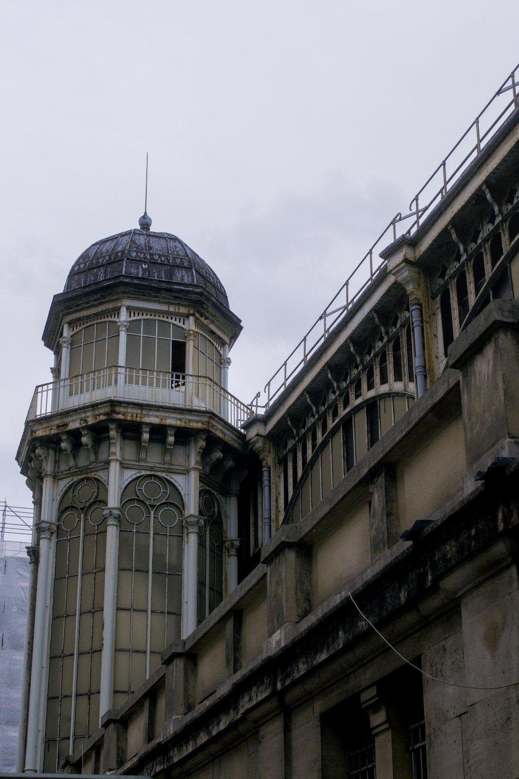 Photo verticale. Une tour étroite au coin d’un bâtiment sous un ciel gris