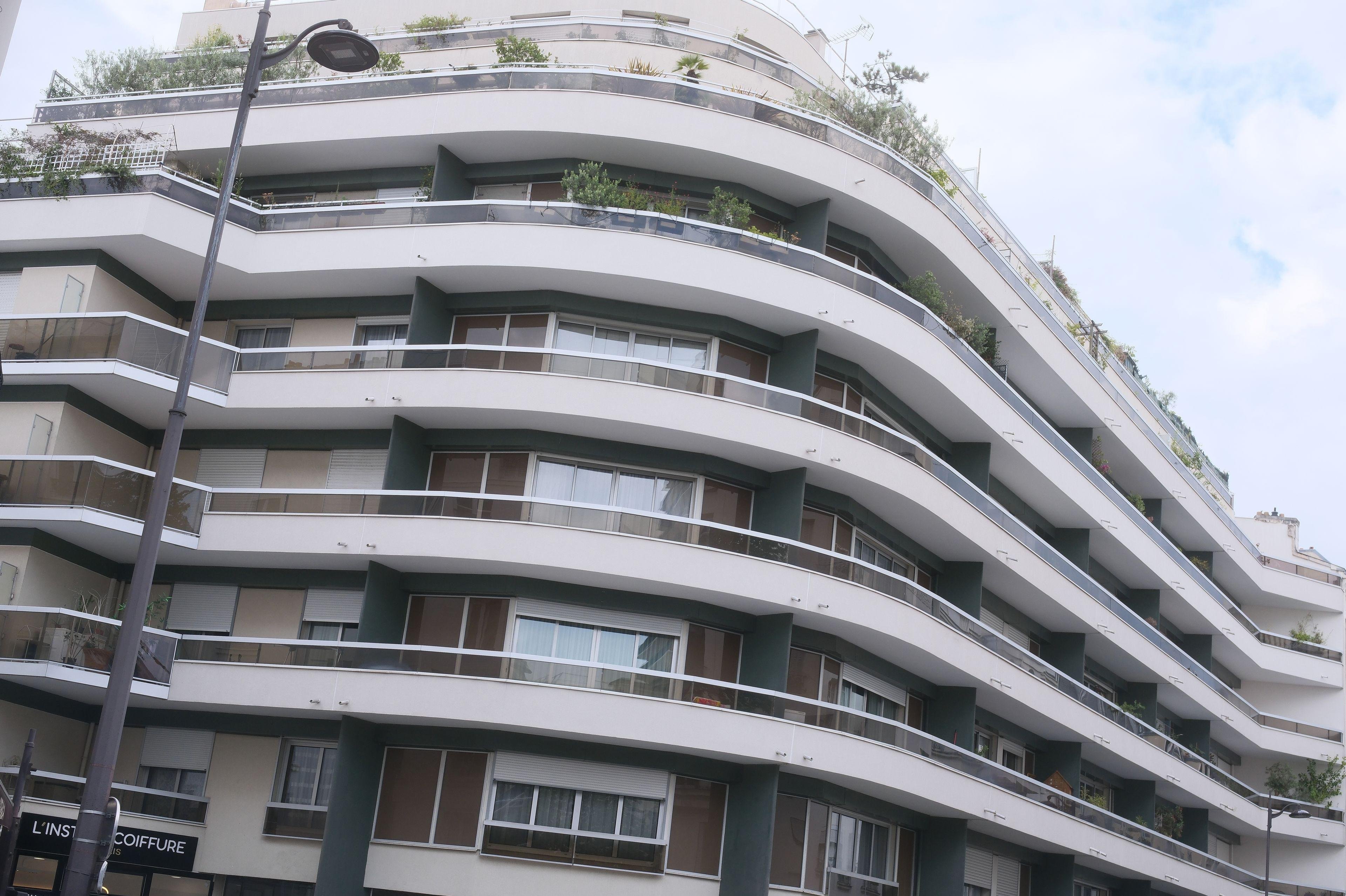 Un immeuble blanc moderne qui n’est pas tout rectangulaire. Une grande courbe à un angle et des angles à chaque bouts