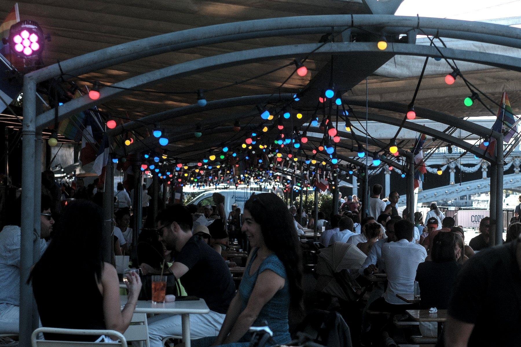 Photo horizontale. Vu sur une terrasse couverte décorée avec une guirlande de lampes de différentes couleurs
