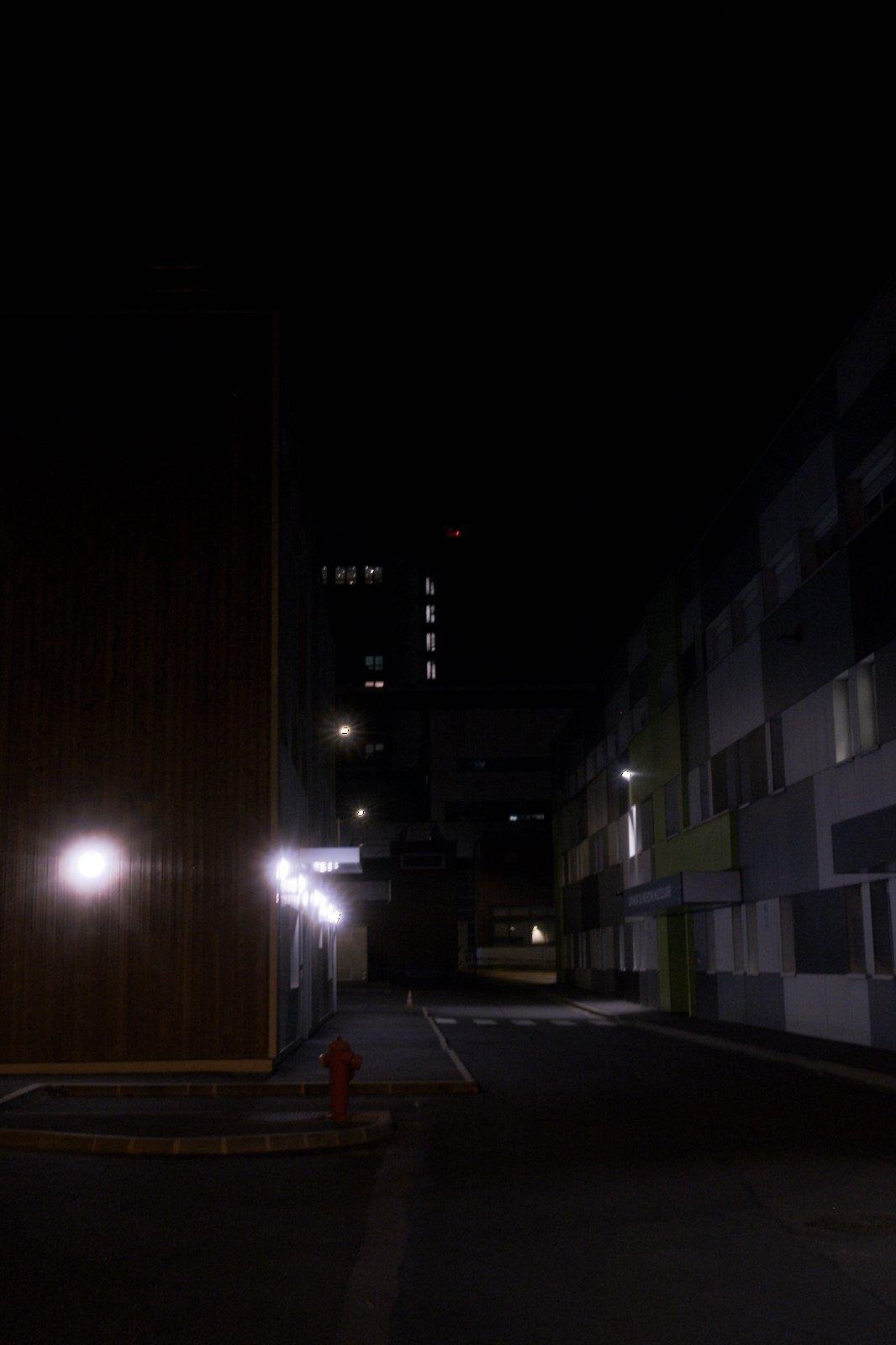 Photo verticale de nuit. Une ruelle obscure déserte, éclairée par des lampes blafarde