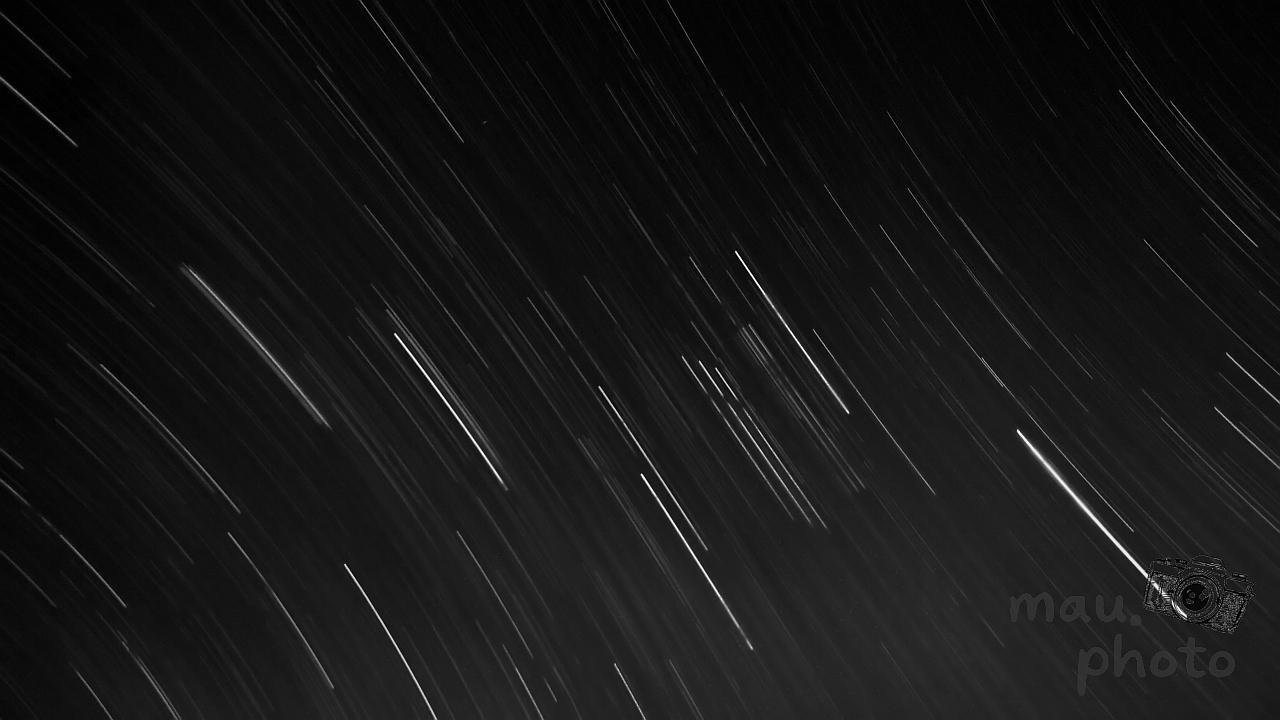 The image shows star trails against a dark sky background. These trails are captured through long-exposure photography, which records the apparent motion of stars across the sky due to the Earth's rotation, creating streaks of light.