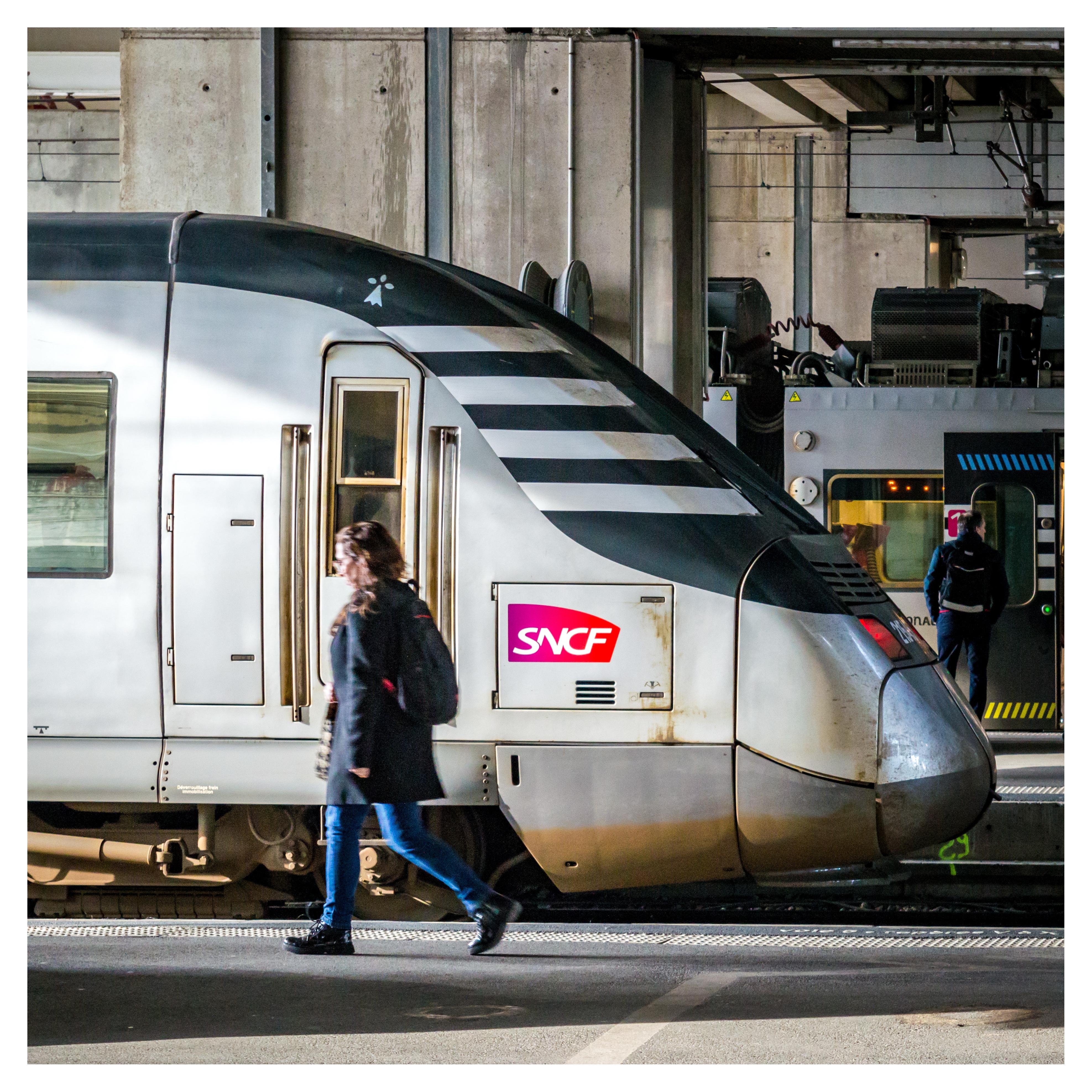 Square photo of a person walking in front of TER BreizhGo train, Rennes