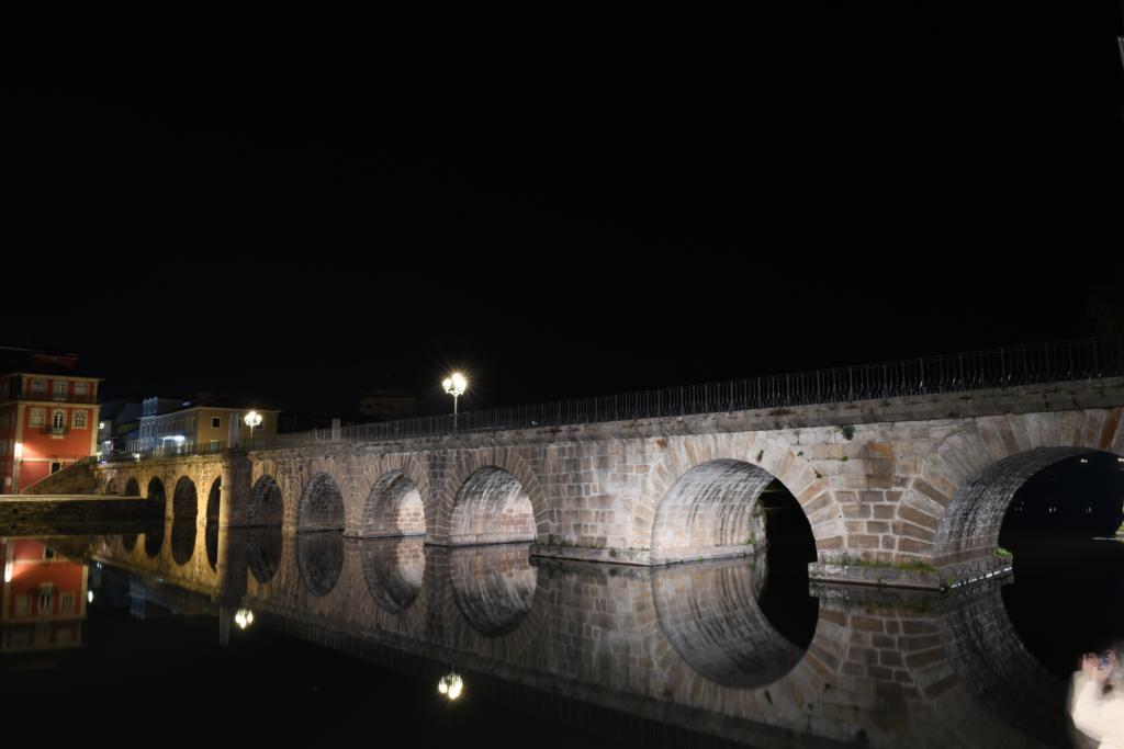 El puente romano sobre el río Támega de noche, con su propio reflejo en el agua.