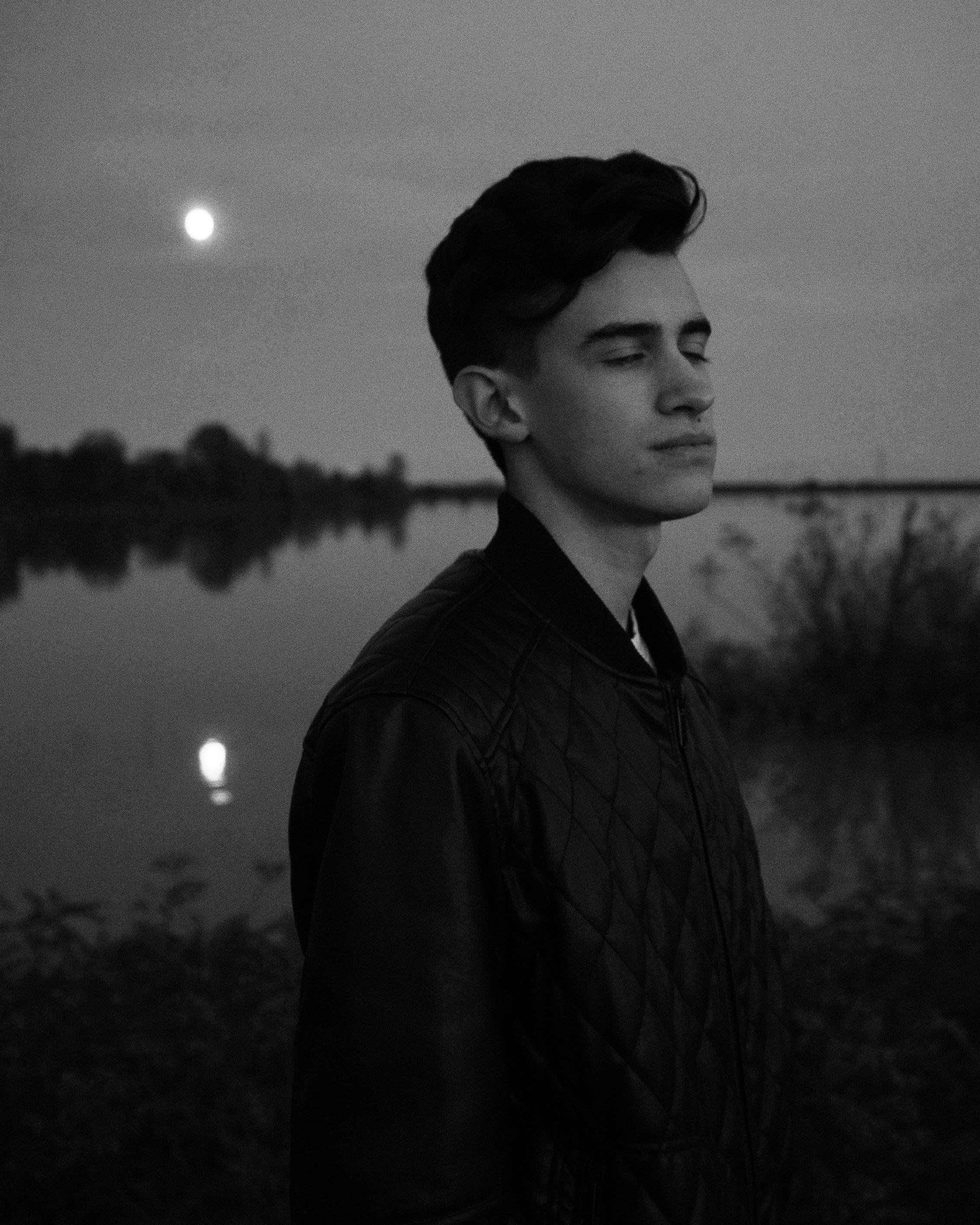 a boy in front of a landscape with the moon