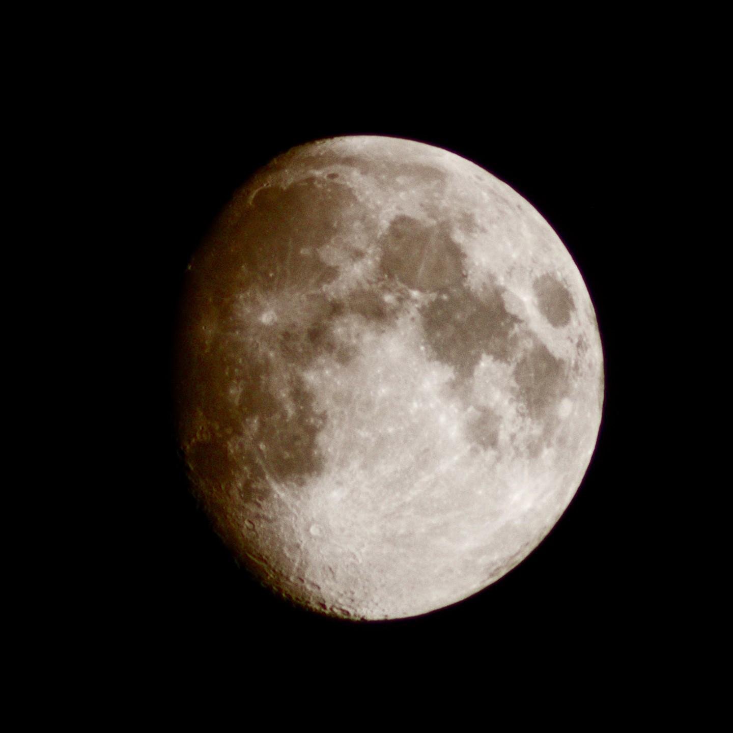 The image shows a close-up of the Moon against a dark background. It appears to be in a waxing gibbous phase, with visible craters and surface details.