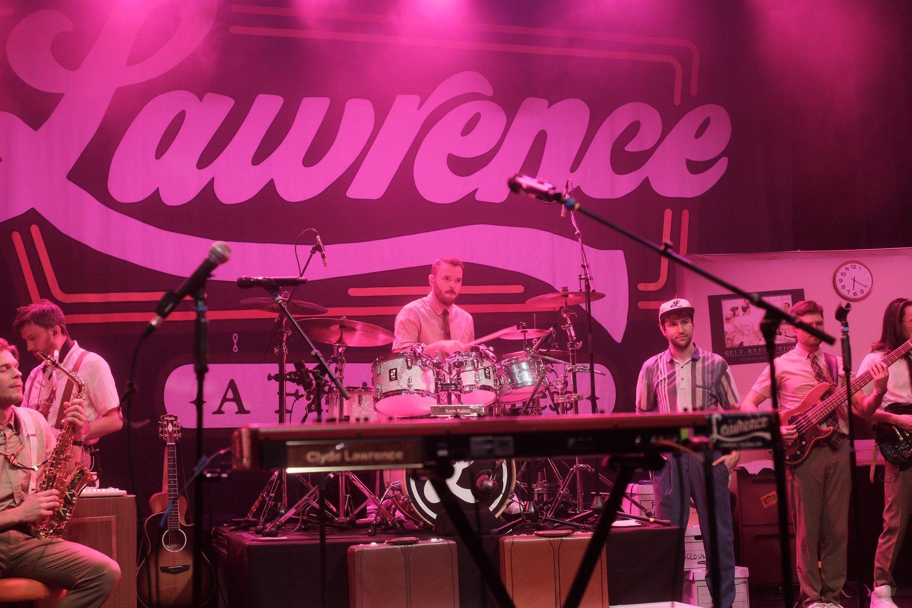 Photo horizontale. Le batteur du groupe Lawrence, sous un éclairage très magenta