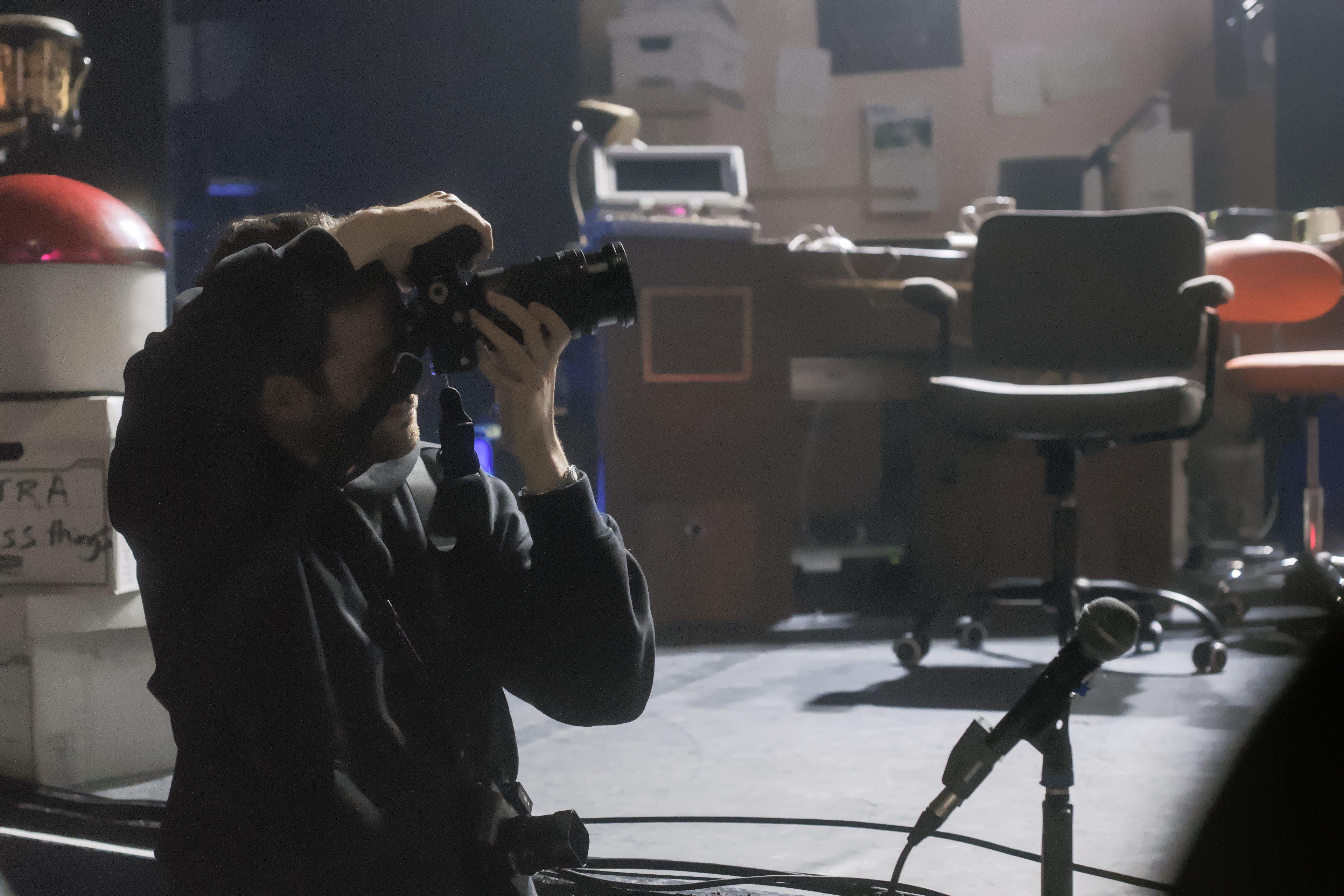 Photo horizontale. Un photographe professionnel sur les abords d’une scène de concert, en train de prendre une photo