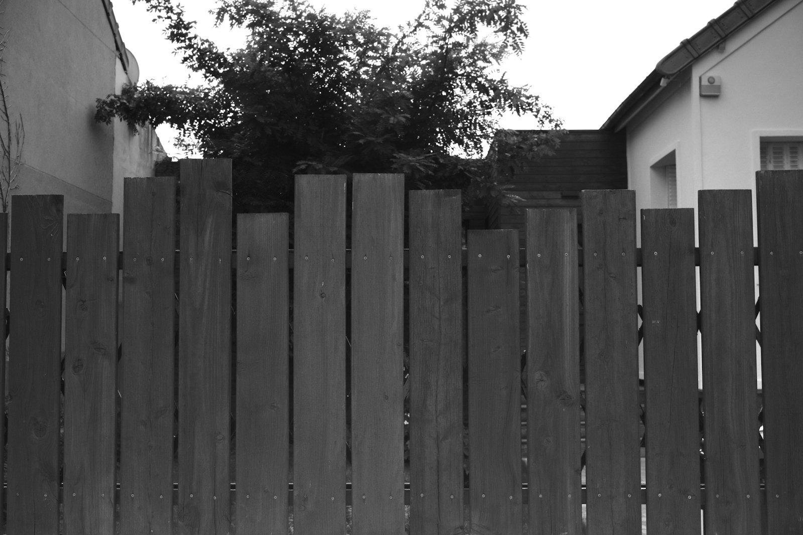 Photo horizontale noir et blanc. Une palissage en bois de face, mais les planches ne sont pas ajourée, donnant une impression d’un equalizer audio