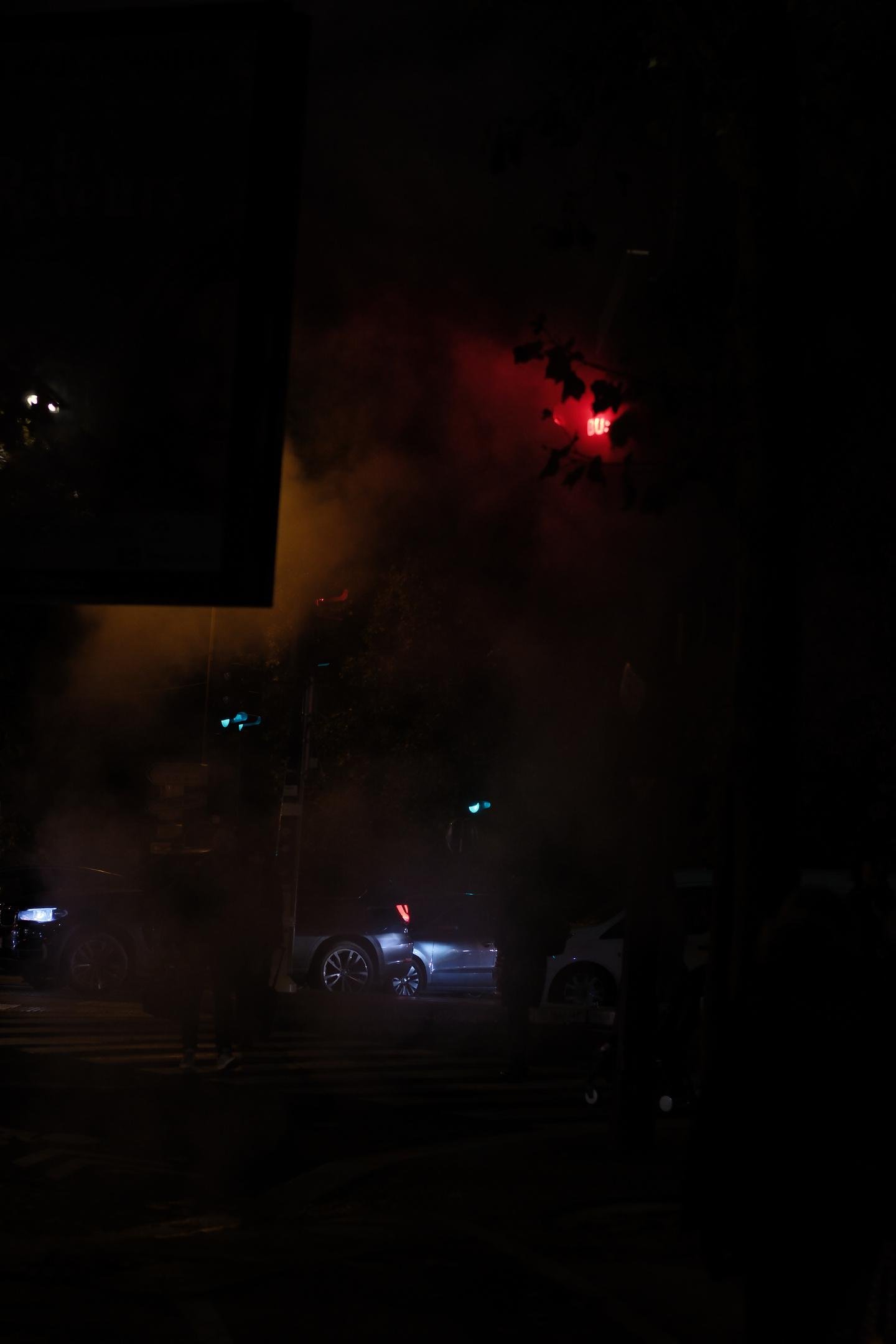 Photo verticale, de nuit. Un feu tricolor au rouge émet sa lumière à travers de la fumée