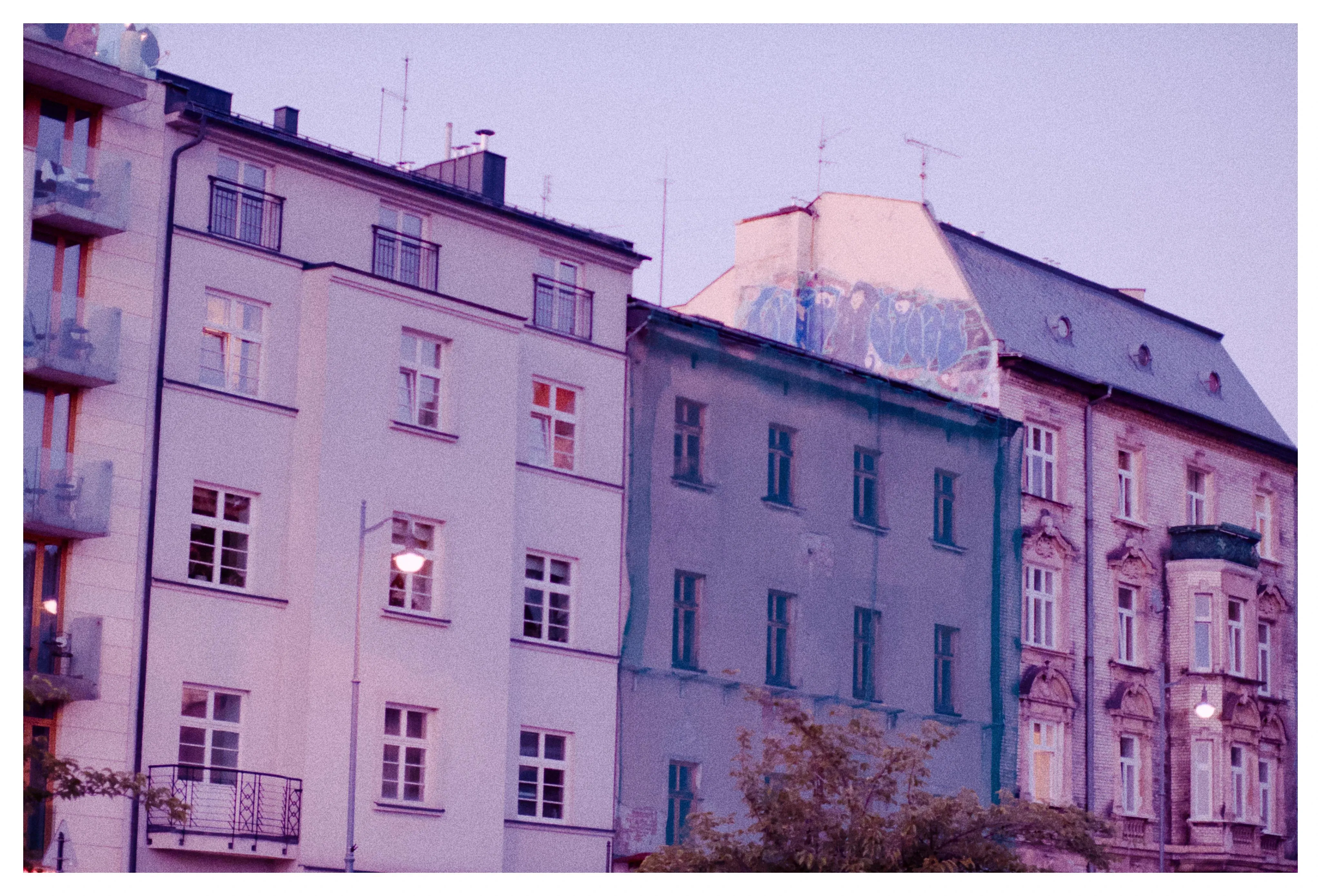 A heavily colorized photo of three buildings stacked next to each other, on the last one there is a graffiti on the rooftop 
