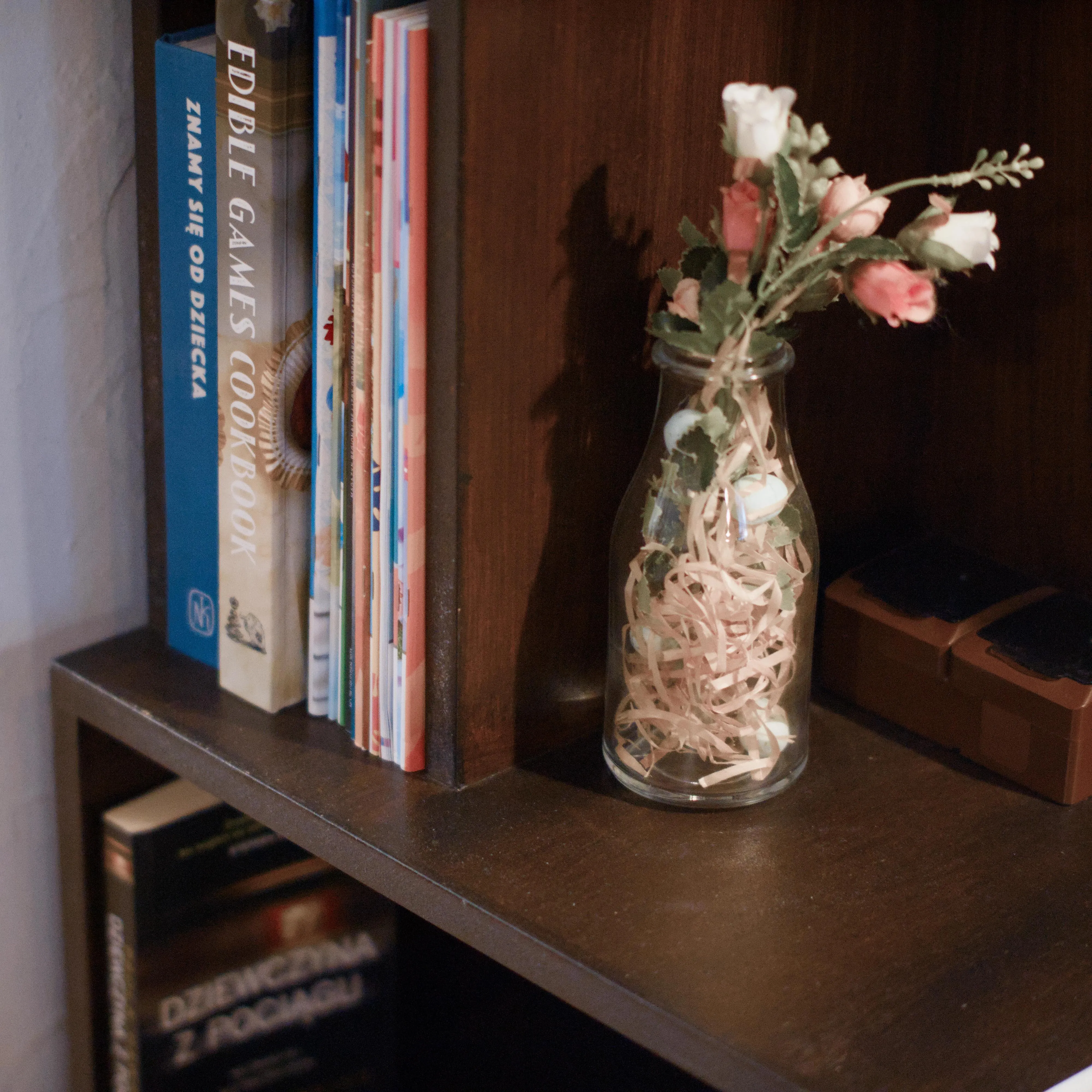 A photo of a wooden bookshelf with a flower vase