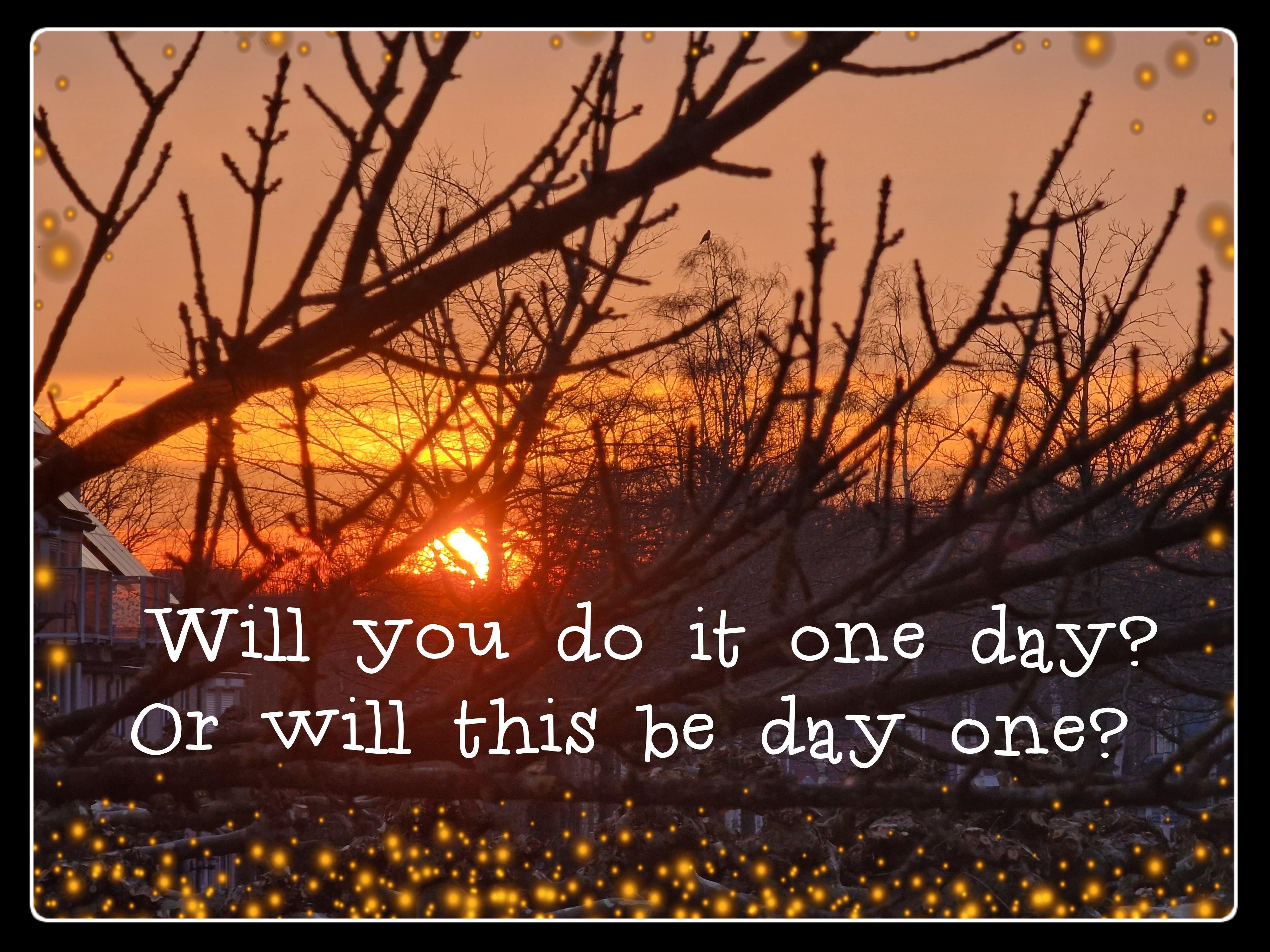 A tranquil early morning scene featuring a vivid sunrise casting warm hues of orange, red, and gold across the sky. The sun is partially visible, peeking through a delicate lattice of bare tree branches that stretch upward, silhouetted against the glowing horizon. The trees, devoid of leaves, create an intricate web of dark lines that contrast beautifully with the radiant sky. In the lower left corner, rooftops of suburban houses are faintly visible, grounding the scene in a quiet residential neighborhood. Scattered throughout the image are small, glowing yellow dots resembling fireflies or magical sparkles, adding a whimsical and enchanting touch. Overlaid in a playful white font is a motivational quote: 'Will you do it one day? Or will this be day one?'—encouraging reflection and action as the day begins.