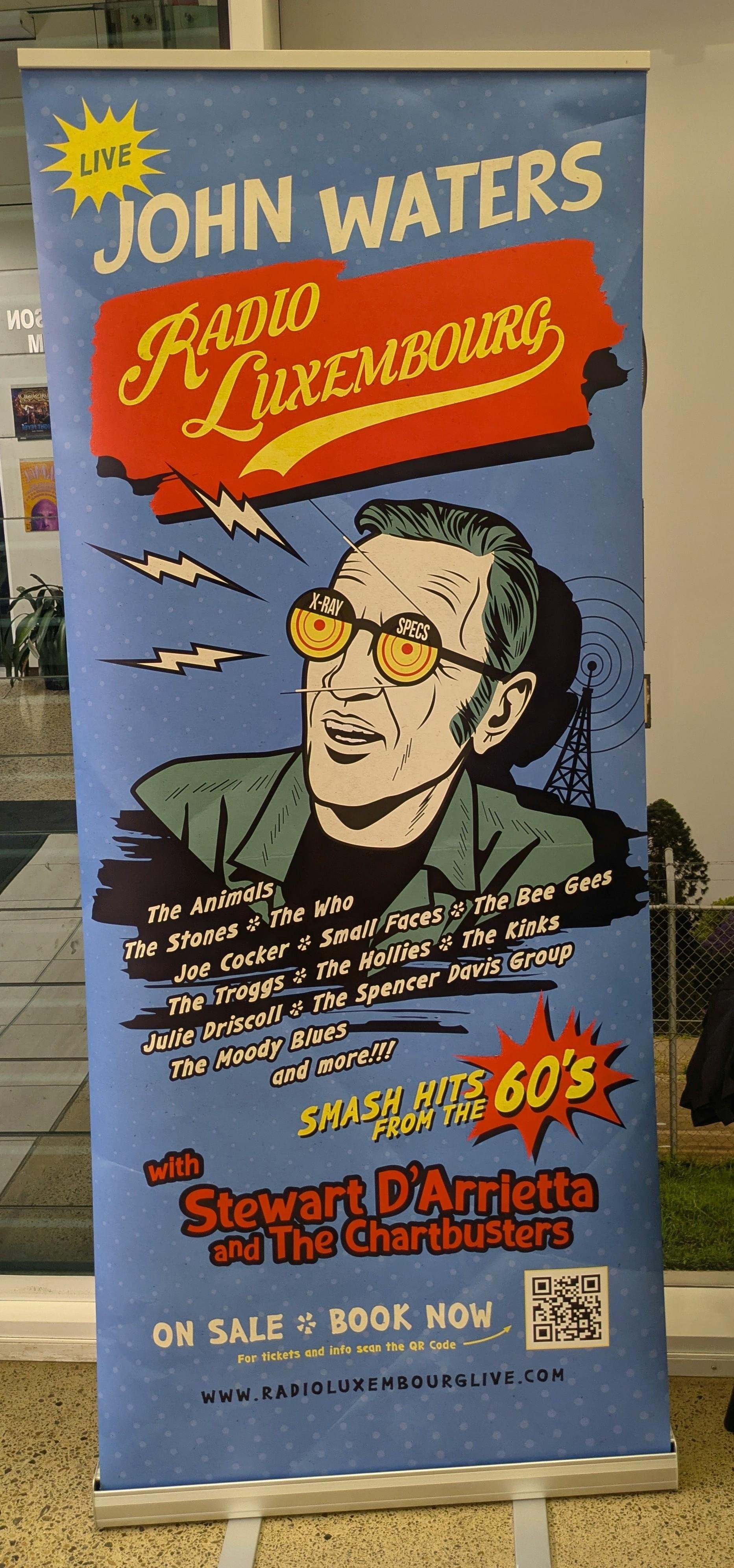 Poster for "Radio Luxembourg" featuring a comic-style illustration of a person with "X-Ray Specs" on their glasses. Announcements include live performances by acts like The Animals, The Who, The Bee Gees, and more, highlighting "Smash Hits from the 60s" with Stewart D'Arrietta and The Chartbusters. Contains phrases like "Book Now" and a QR code, with a blue background and red, yellow, and white text.