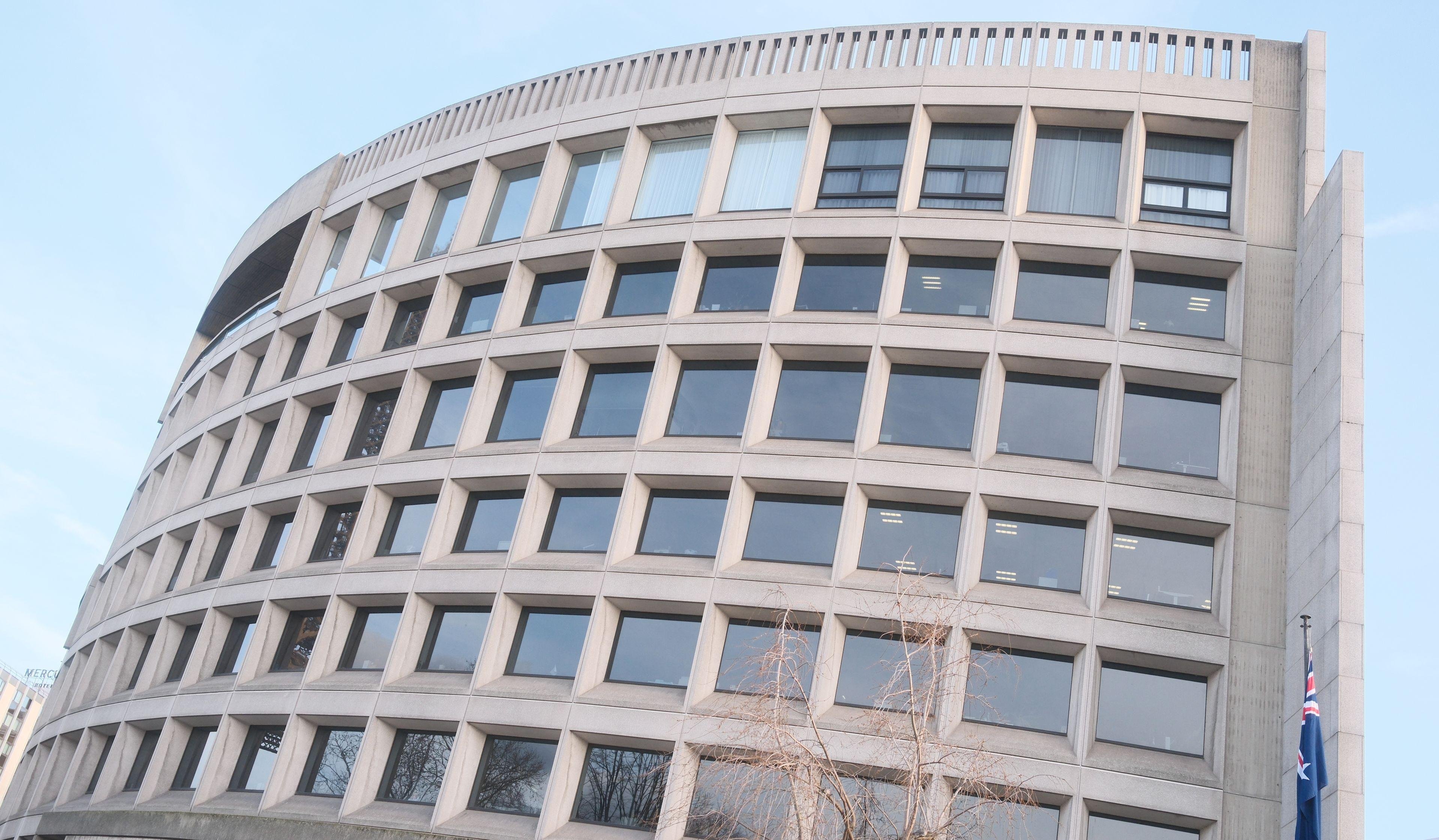 Photo horizontale. Un immeuble d’environ 6 étages en léger arc de cercle, plein de fenêtres carrées