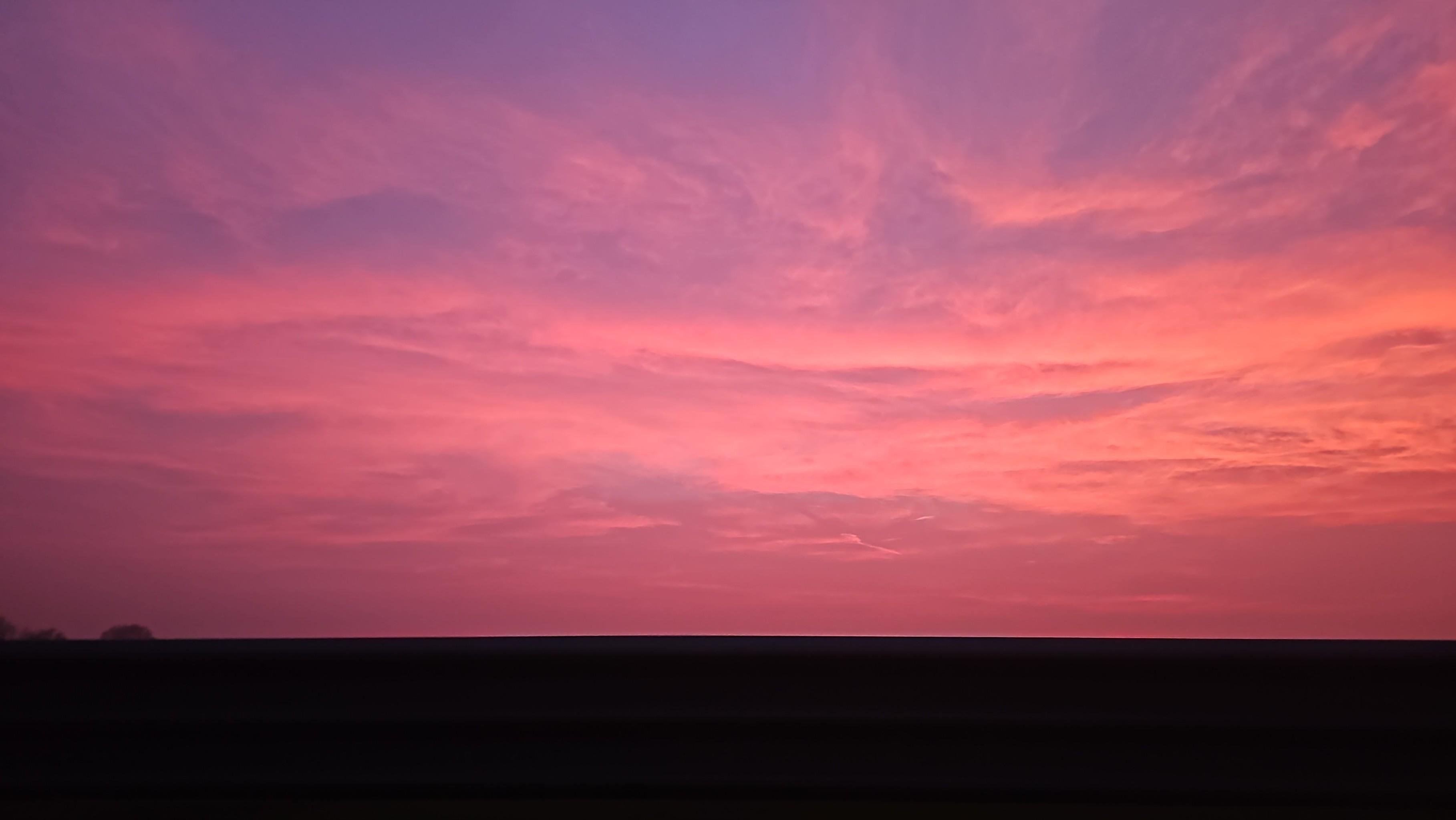 Tramonti di porpora...

The image shows a beautiful sunset or with a sky filled with vibrant pink and purple hues. The horizon is dark, suggesting an outline of land or a silhouette of trees beneath the colorful sky.