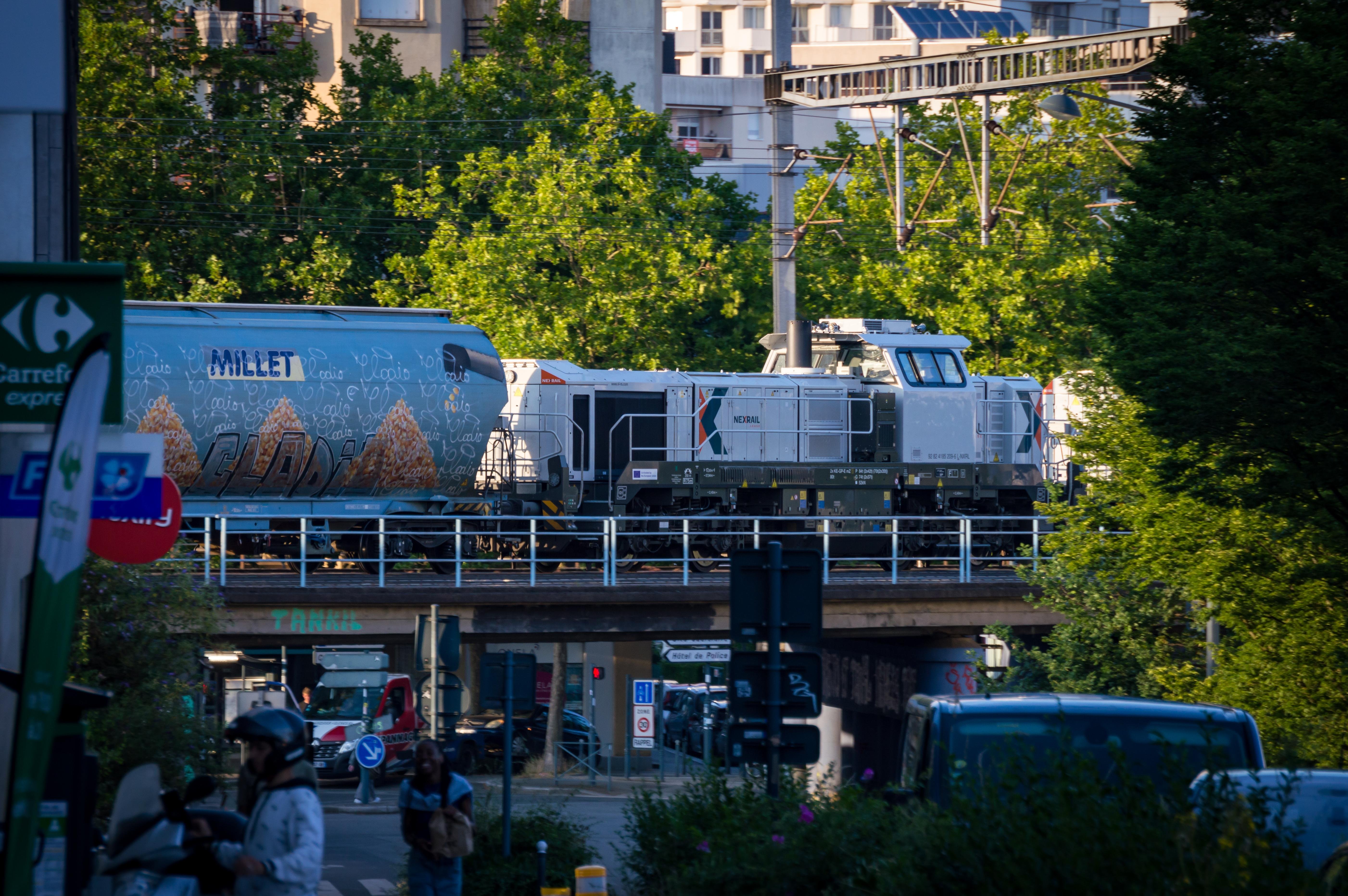 Freight train with grain passing through a bridge in the middle of the city