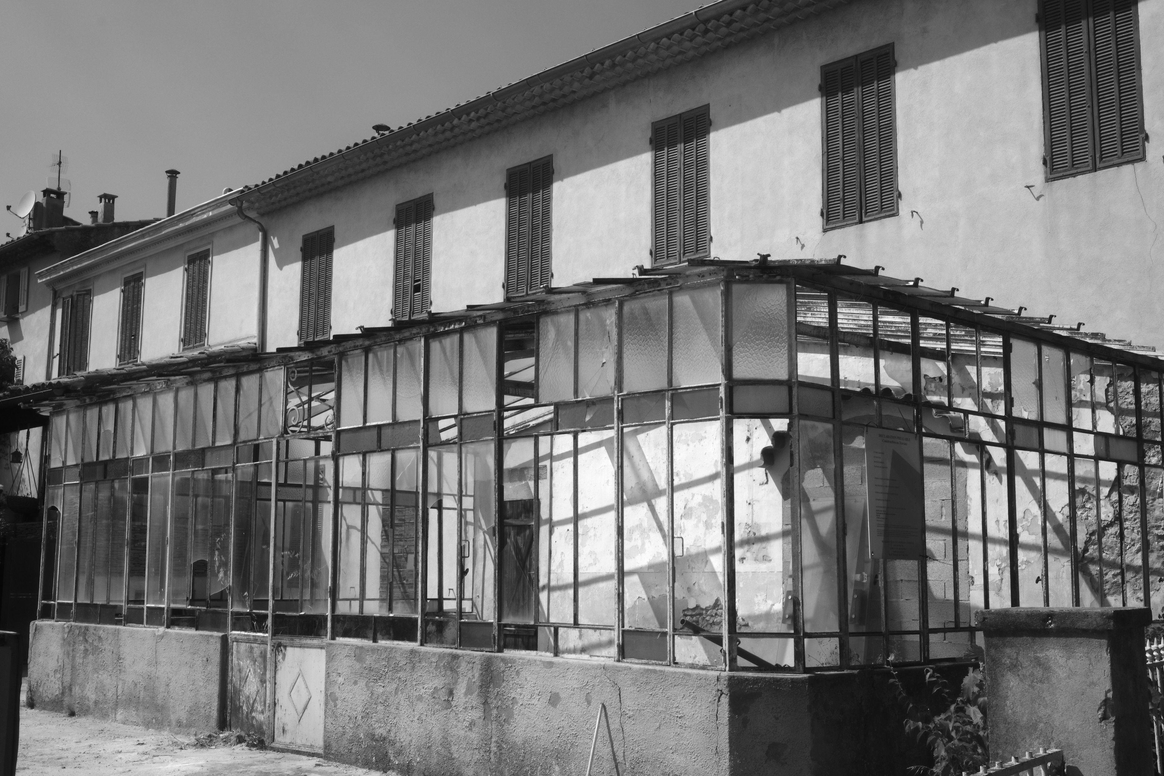 Photo horizontale en noir et blanc. Une véranda abandonnée avec des carreaux de vitre manquantes