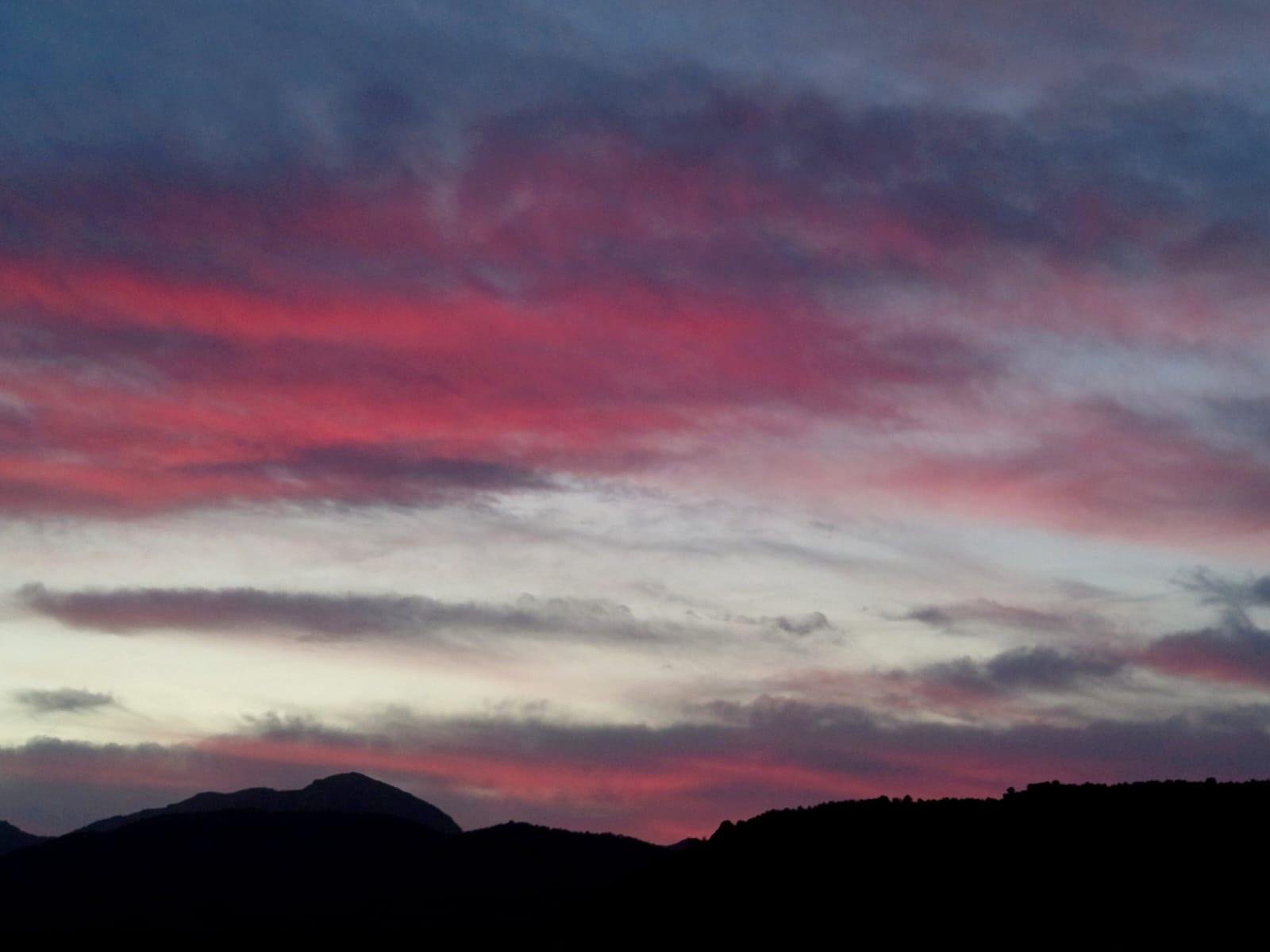 Una puesta de sol de tonos rosas y azules sobre la silueta negra de Sierra Espuña