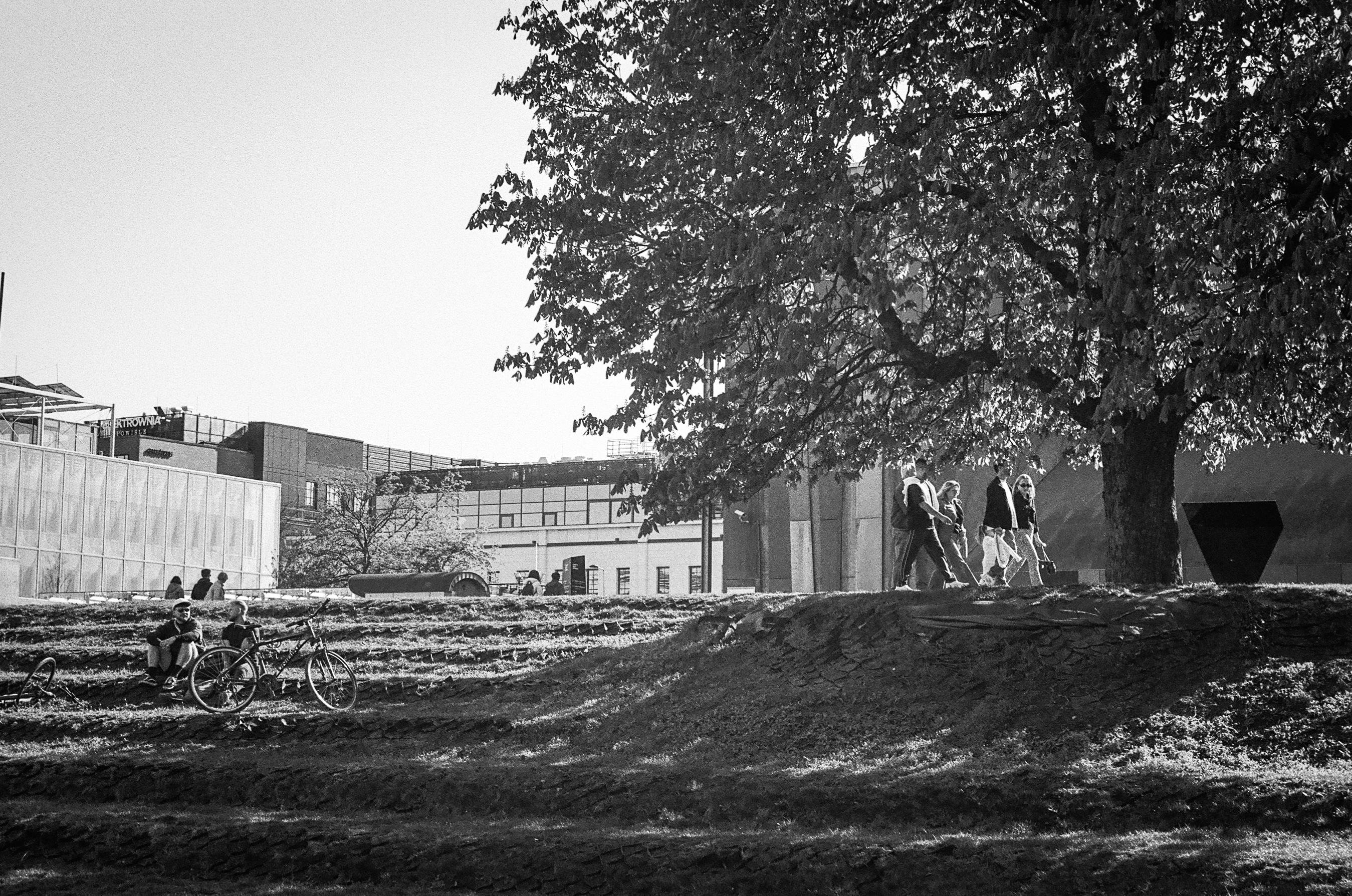 B&W photo of people resting on the grass near Centrum Nauki Kopernik, Warsaw