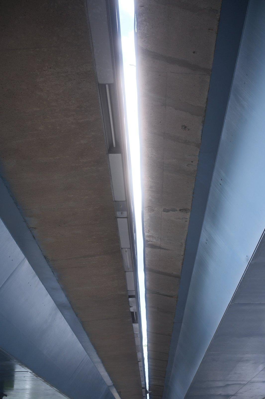 photo verticale, une construction vu de dessous, bleue sur les côtés et marron au centre, coupée au centre, laissant passer la lumière du jour