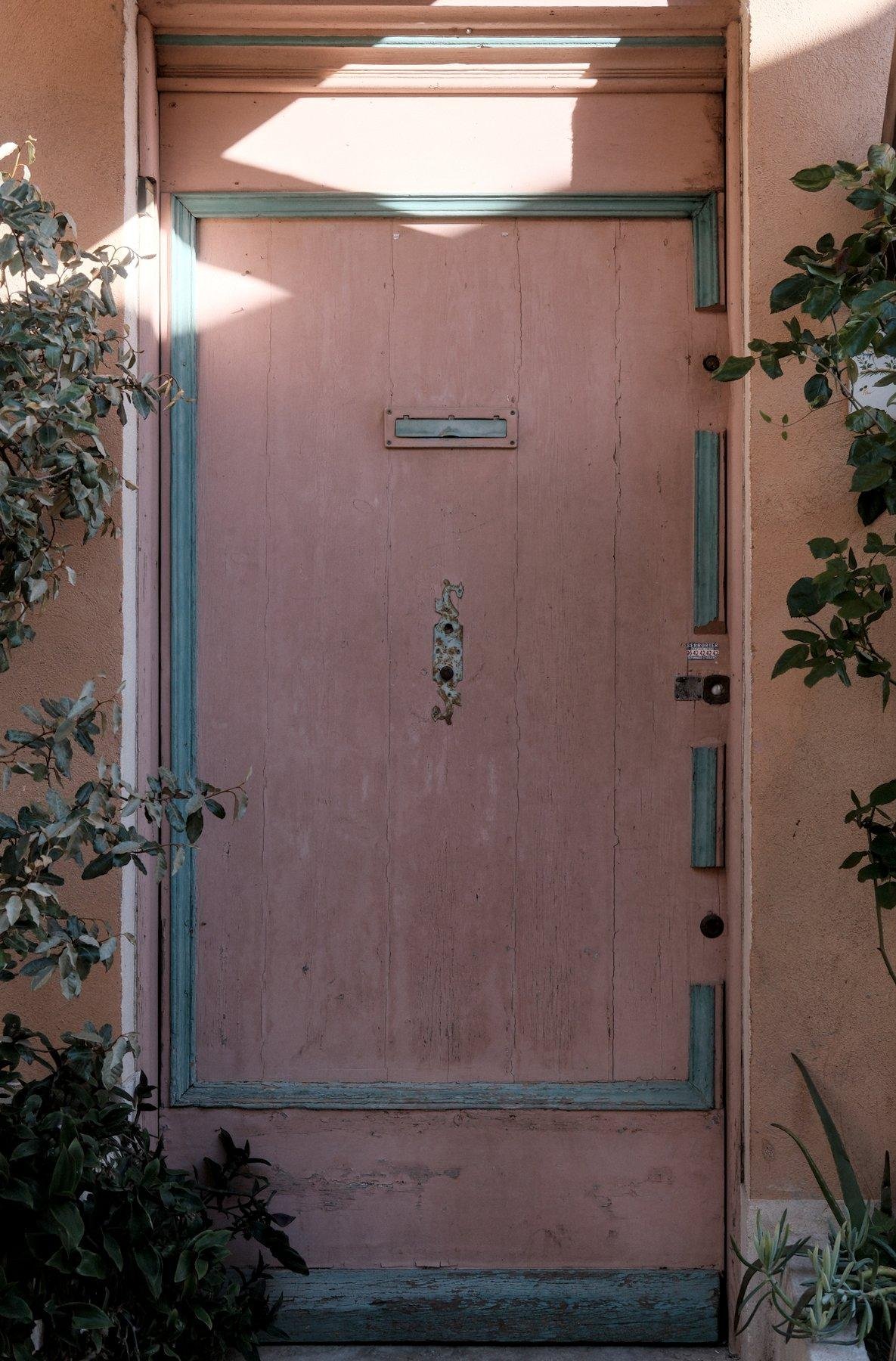 Photo verticale. Une porte couleur saumon et accent gris sur les moulures