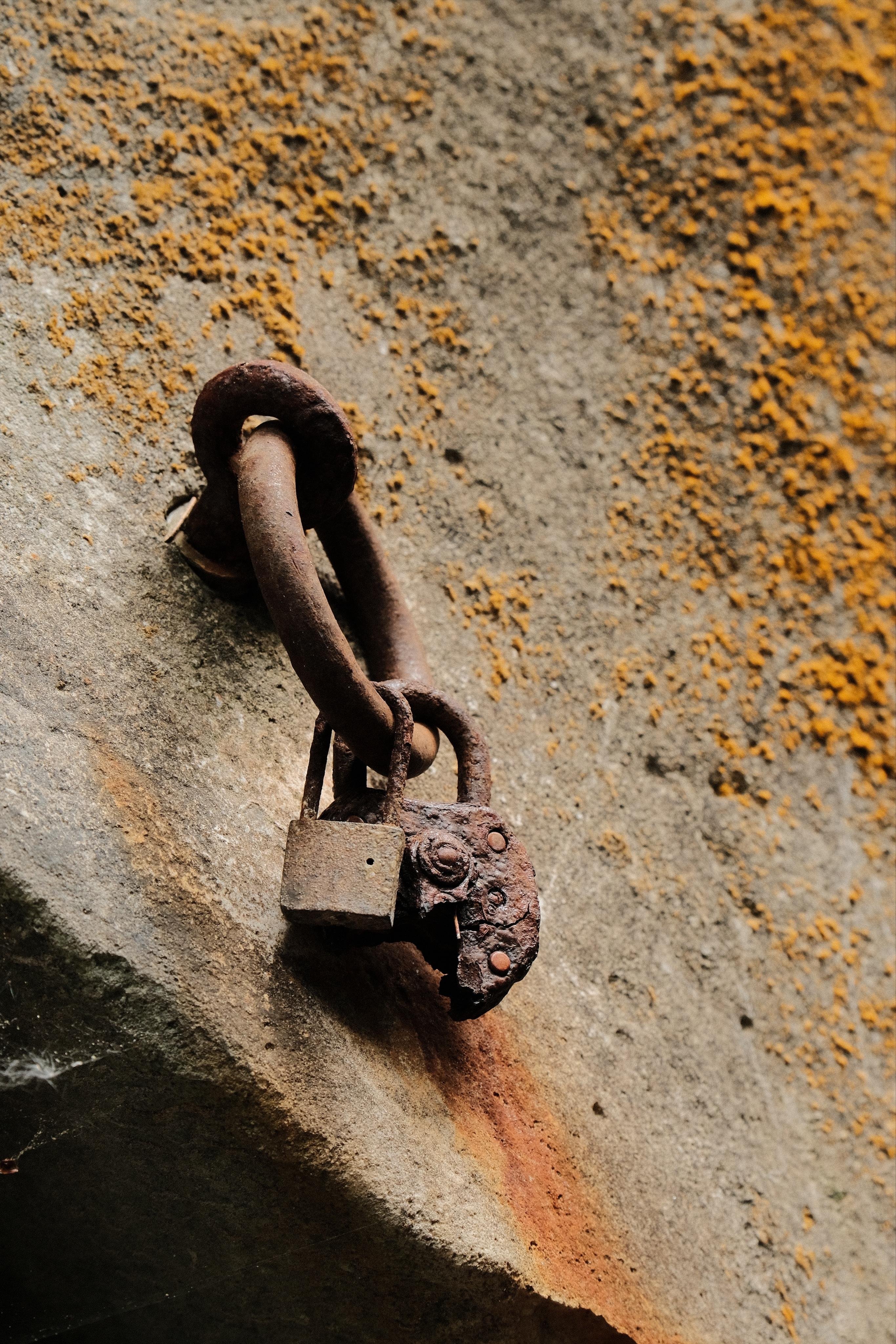 Two padlocks attached to a ring that itself is attached to an anchor in a large rock. All metals parts are heavily corroded by constant exposure to mist and water by the stream which carved the narrow gorge into the rocks (which is not visible in this shot).
One of the padlocks has rusted much more and only half of it is left, the rest must have been ripped away.
On the rock grows yellow-brownish moss.