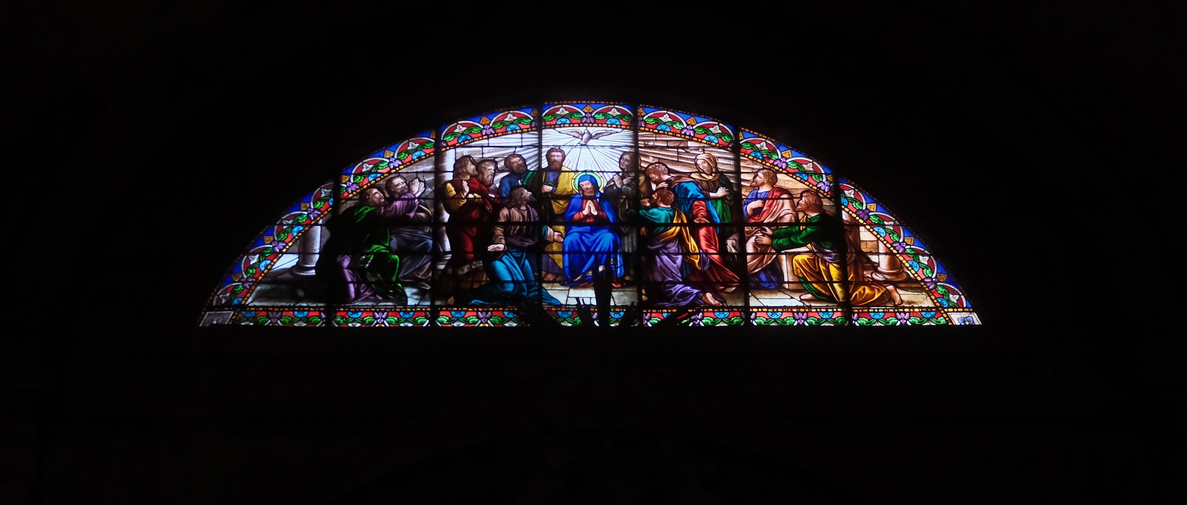 Photo horizontale. Des vitraux ressortent du noir amblant