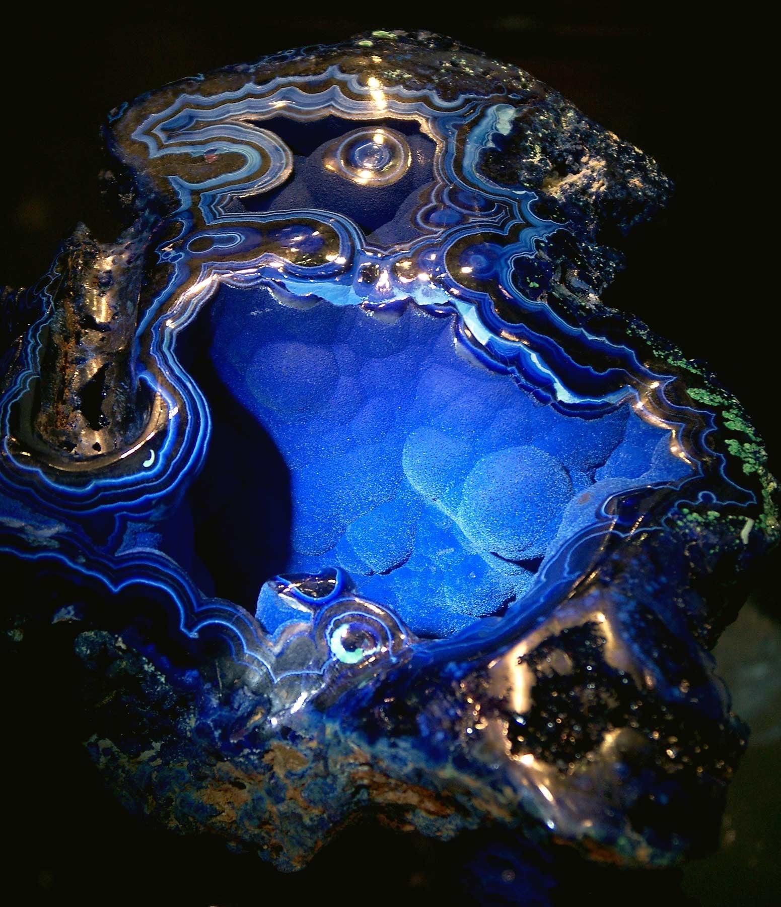 Velvet Beauty—stunning specimen geode from Arizona opened partway up to reveal blue crystals of azurite covering green malachite boytroidal bubble forms inside a rounded sphere geode about 7” diameter. The name is by the owner: in 2007 it was very valuable, about $25,000. There are bands of these minerals and host matrix with quartz that line the interior in layers. The predominate colors are blues from dark almost black solid bands to medium blue crystals to light medium blue fine azurite druzy. Seen in 2007 at the Tucson AZ annual Gem & Mineral show. Taken with a simple point & shoot camera, JPG image.