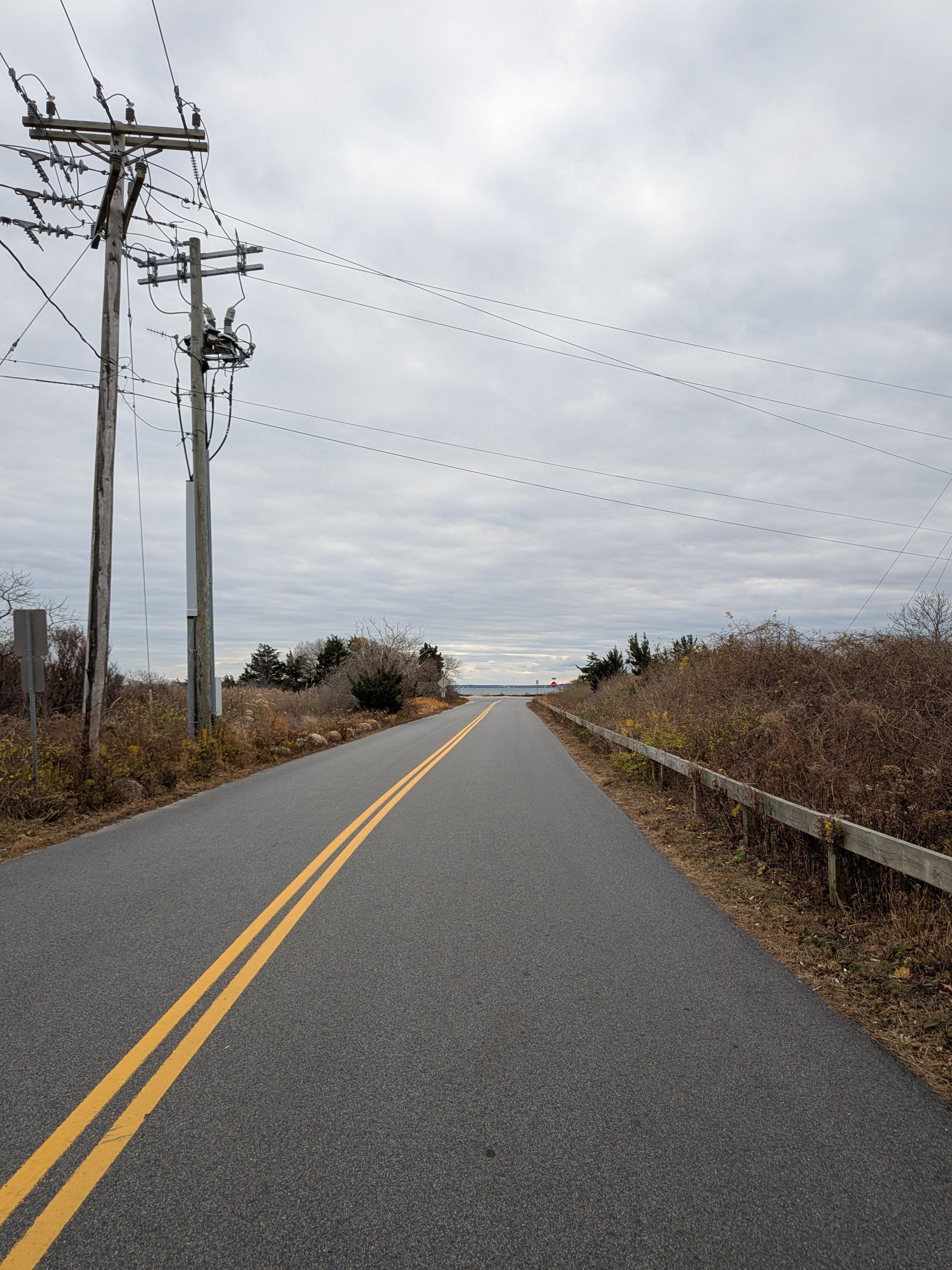 black road into beach with yellow double lines