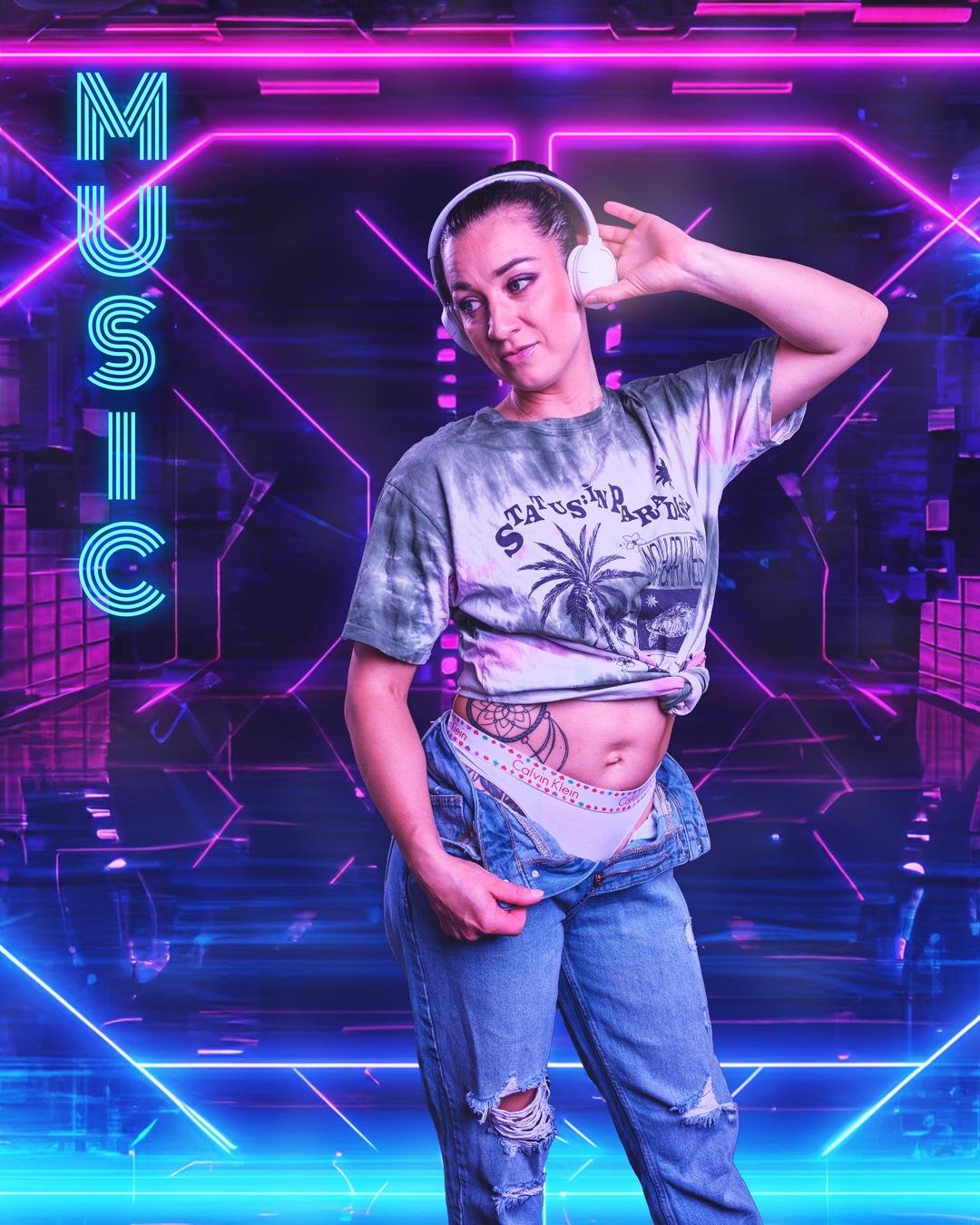 The image shows a person wearing headphones, a tie-dye shirt, and ripped jeans. They have a tattoo on their torso and are standing in a neon-lit environment with futuristic and geometric designs. The word "MUSIC" is displayed on the left side of the image in a bright, illuminated font. Valokuvaaja Lappeenranta Kuvaajankulma