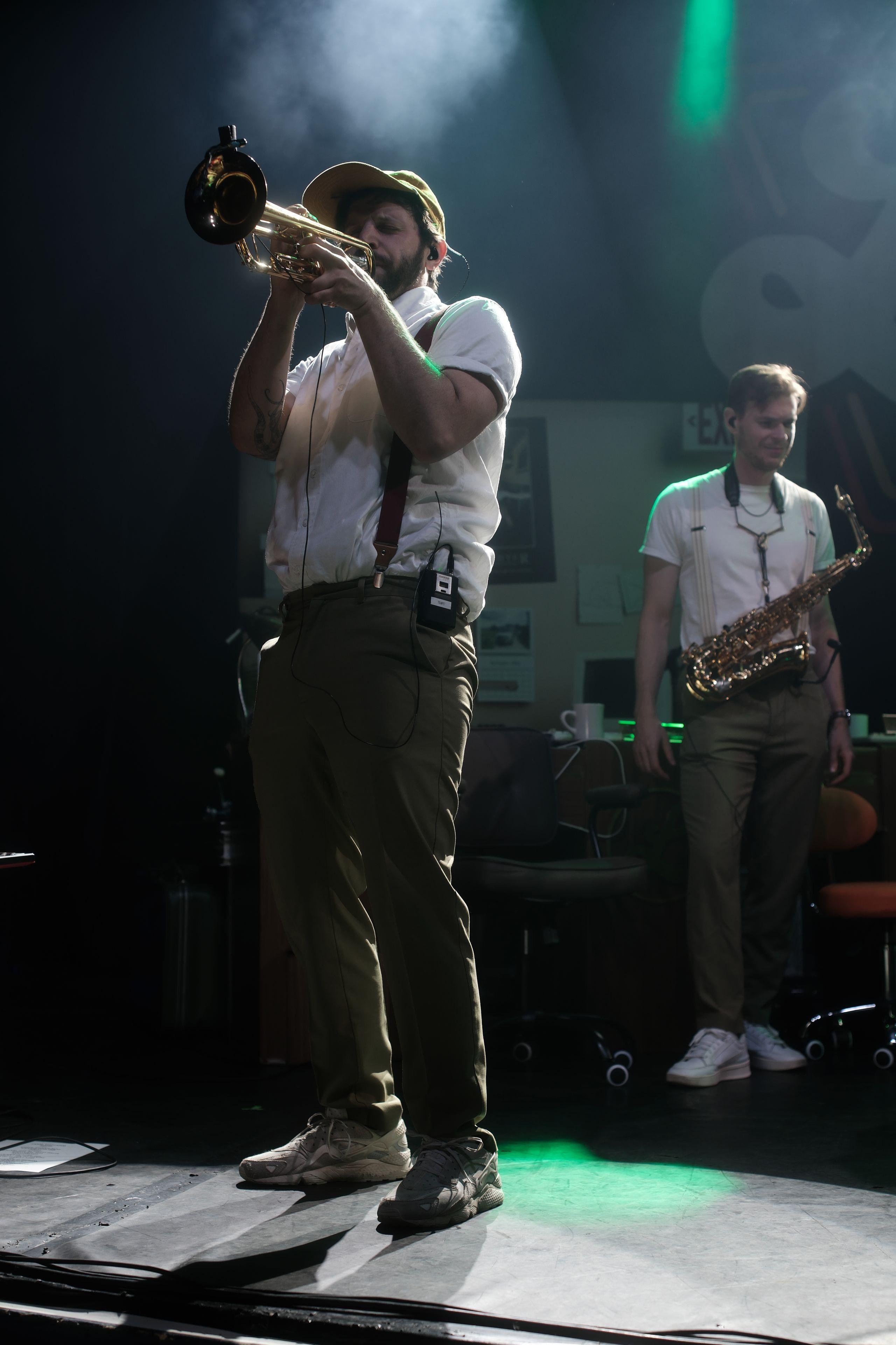 Photo verticale. Un musicien sur scène en plein solo de trompette