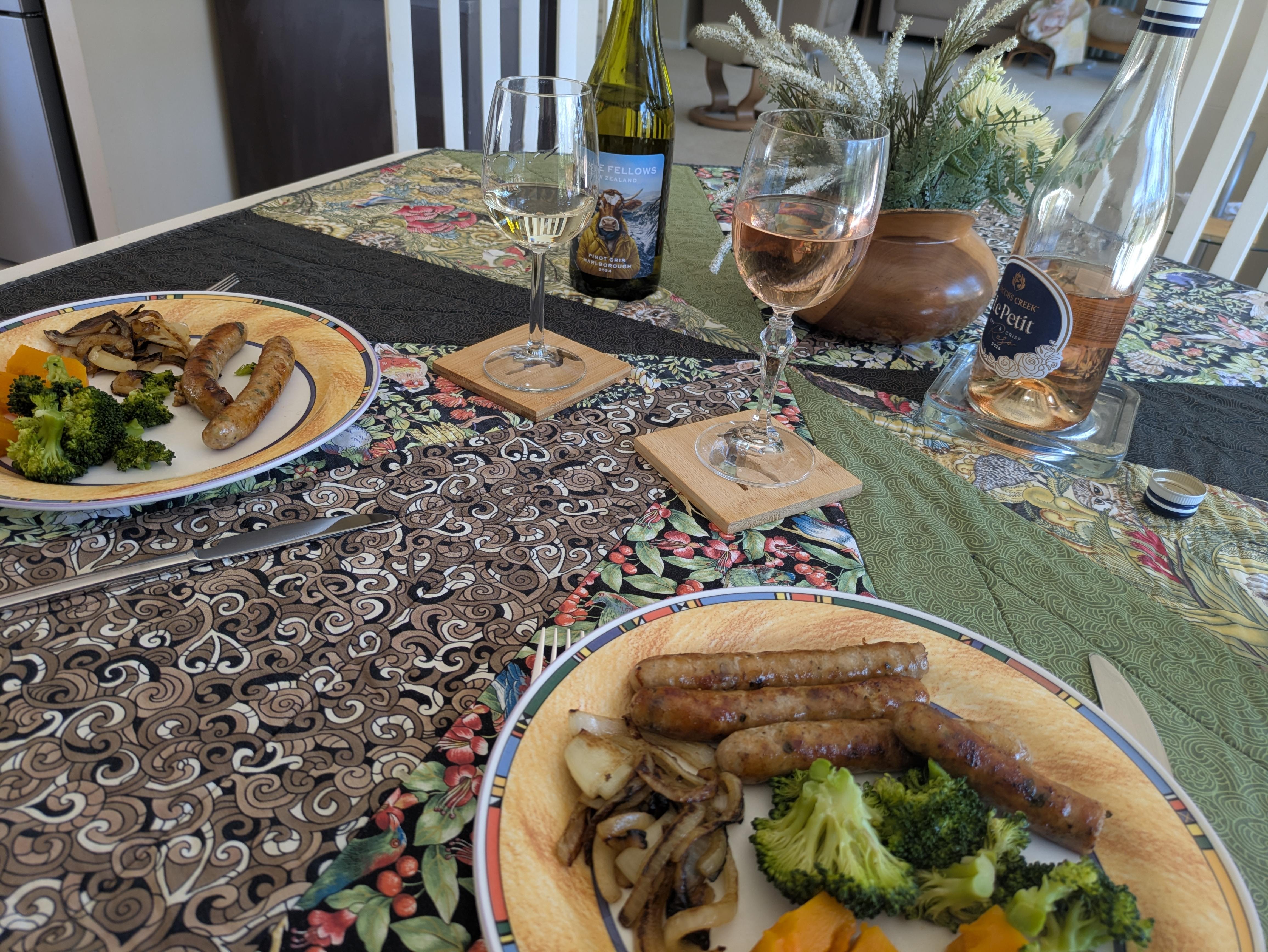 Table set for lunch, with plates of food and  glasses of wine set on special coasters.