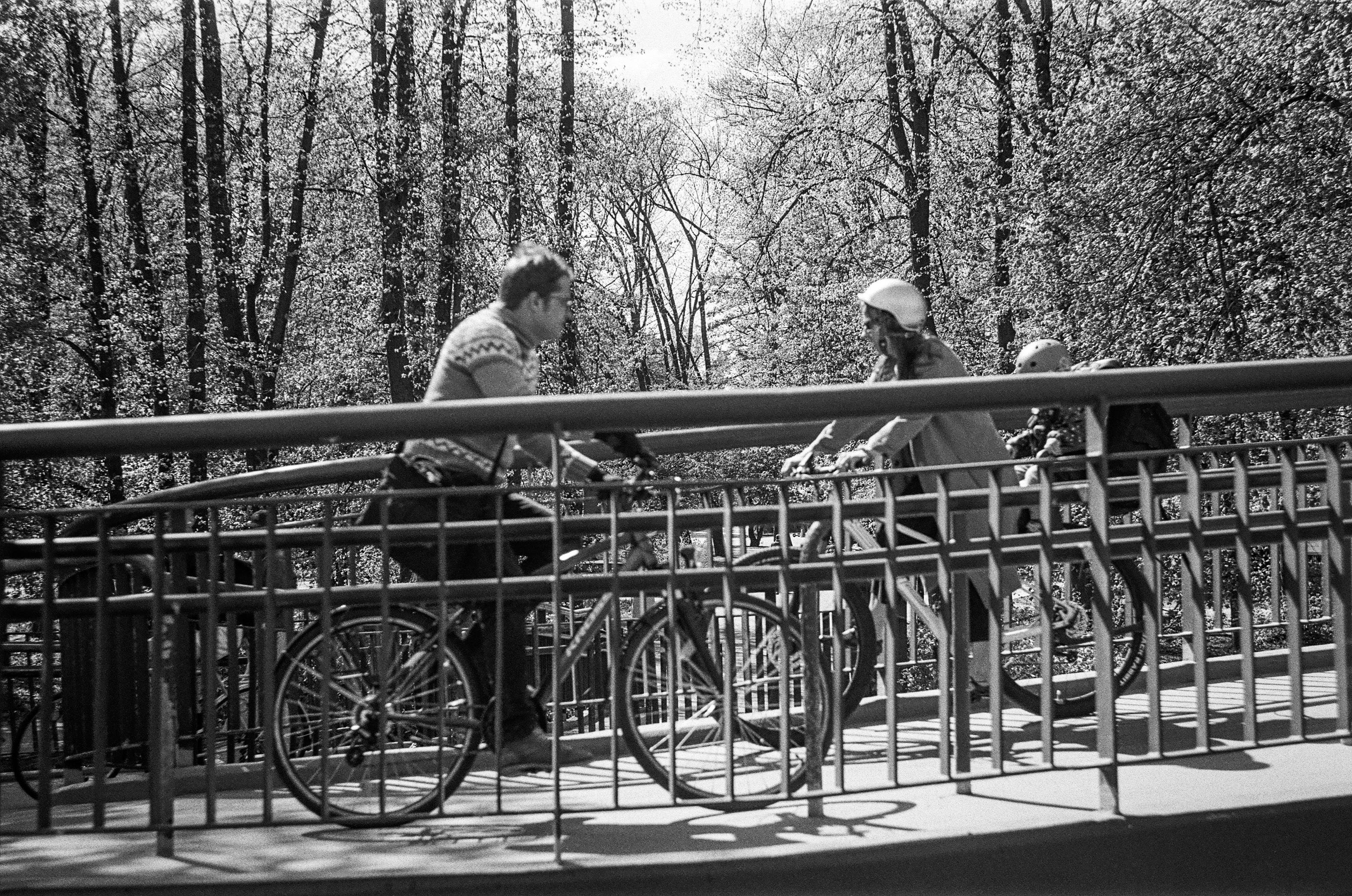 Grainy B&W film photo of people riding bicycles on a ramp 