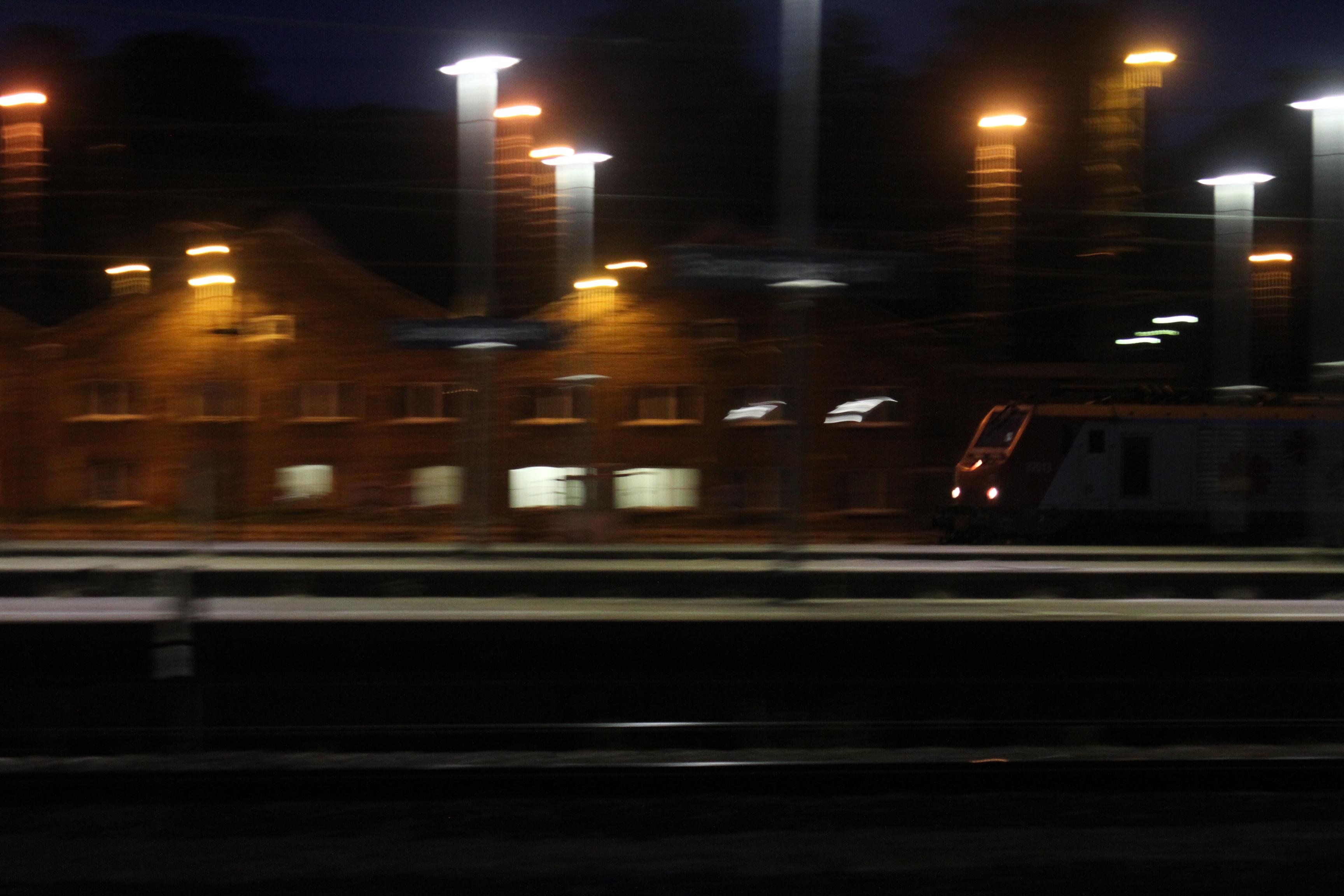 a photo of a train rolling into a train station, the station is blurred while the train is in focus