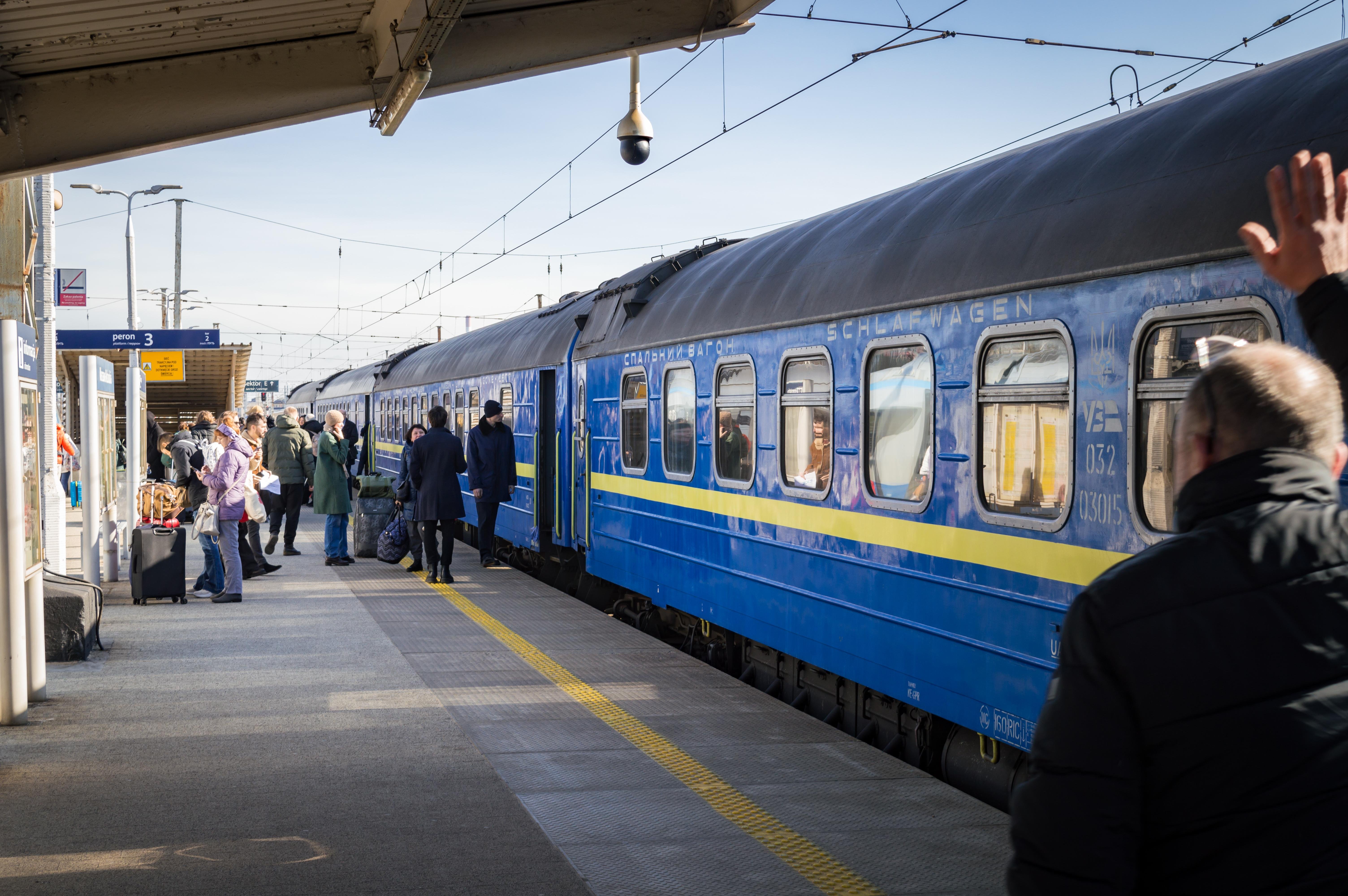 Passengers disembarking from Ukrainian Railways sleeper cars at Warsaw East station. The photo has been photobombed by a man walking towards the crowd and waving at someone in there