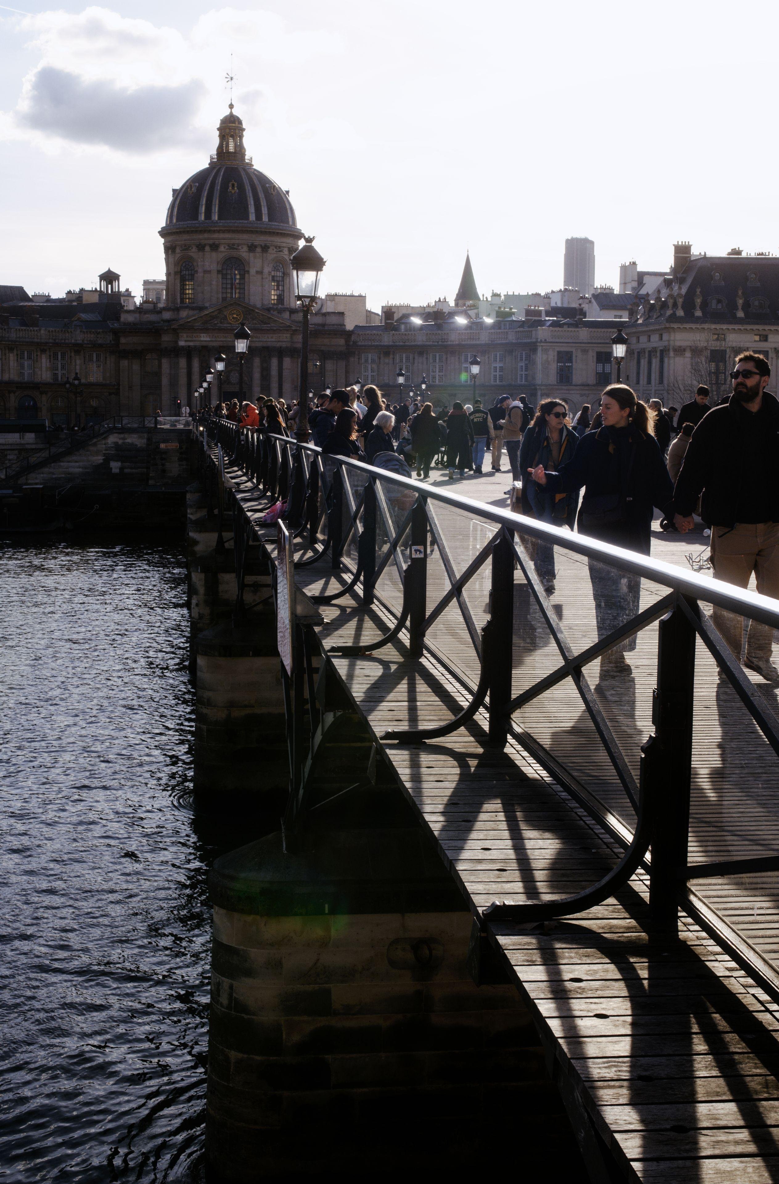 Photo verticale. En perspective, une rembarde du pont des arts va vers le fond le la photo où se trouve l’institue de France et son dôme