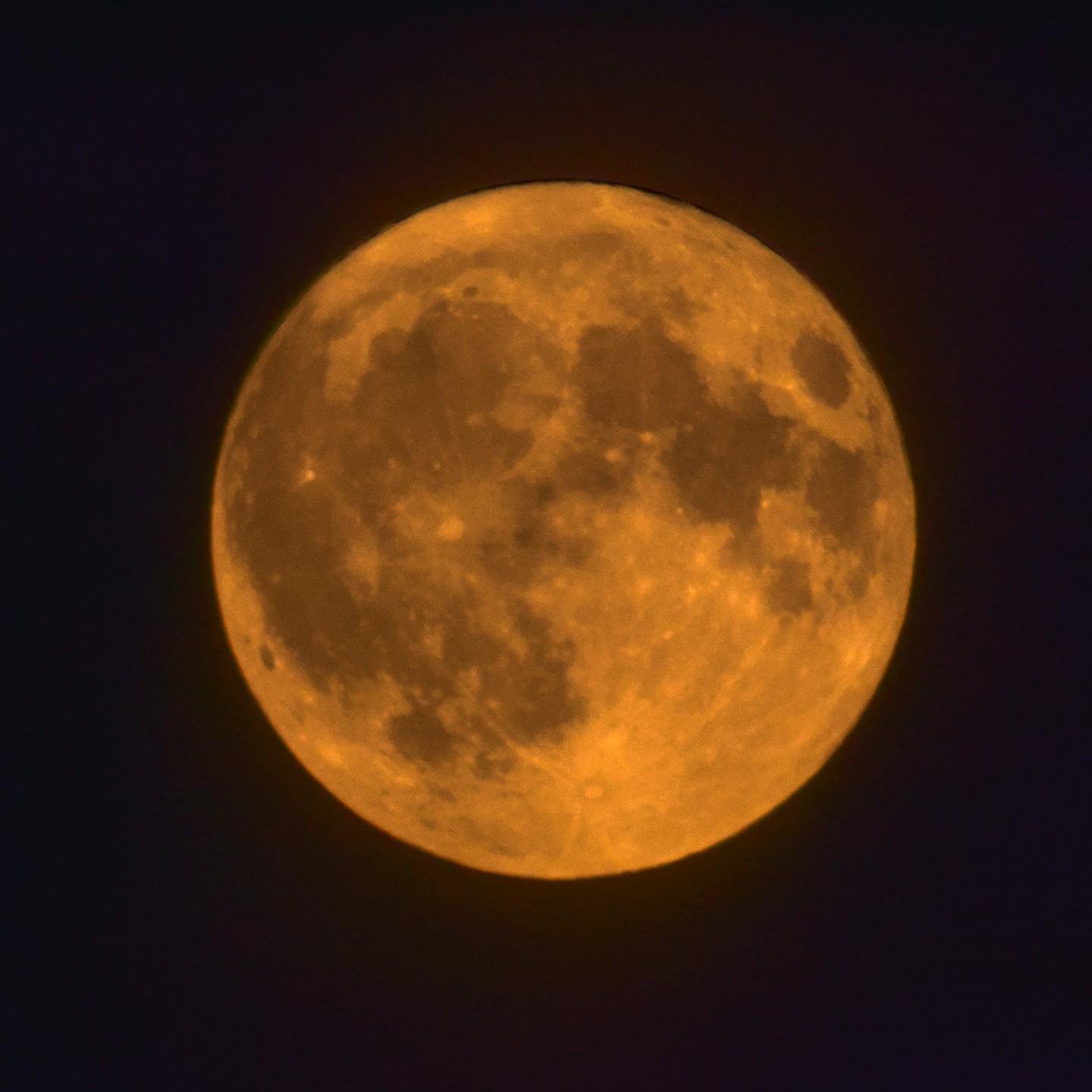 La photo montre une pleine lune avec une couleur orange distinctive.