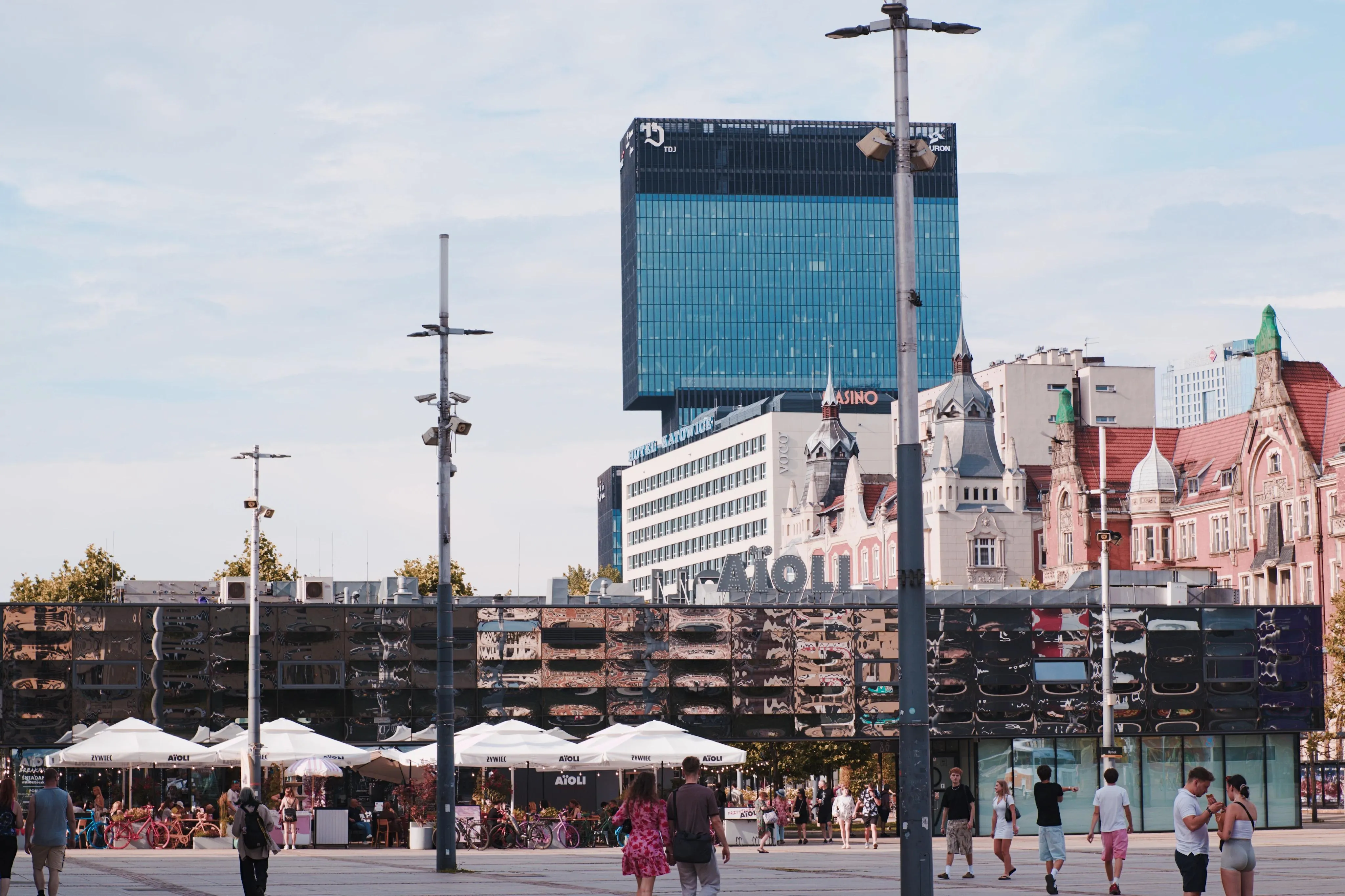 A photo of a cityscape with a long reflective building in the foreground and high skyscraper in the background
