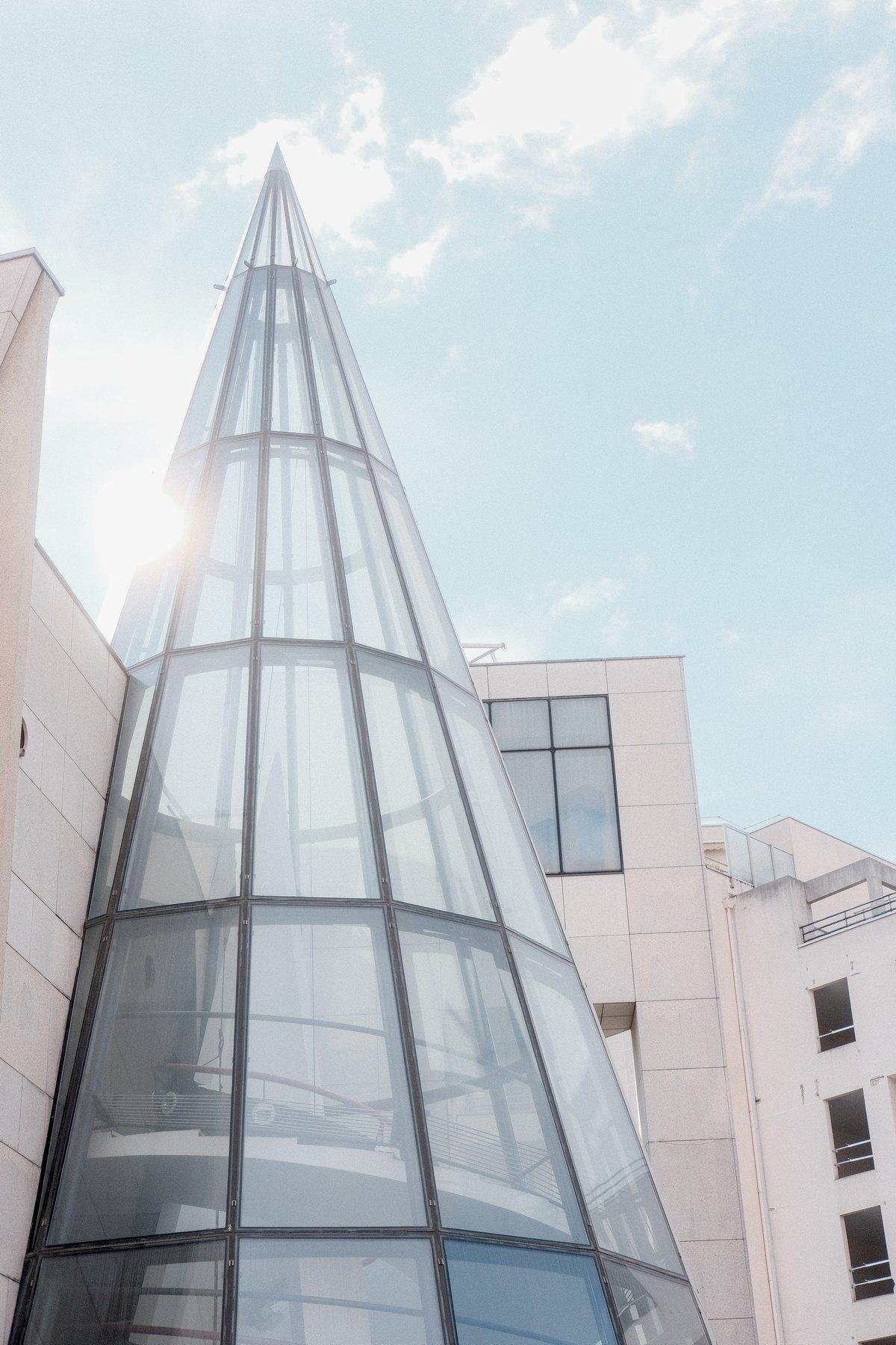Photo verticale. Un grand cone de verre dont la point est vers le ciel bleu