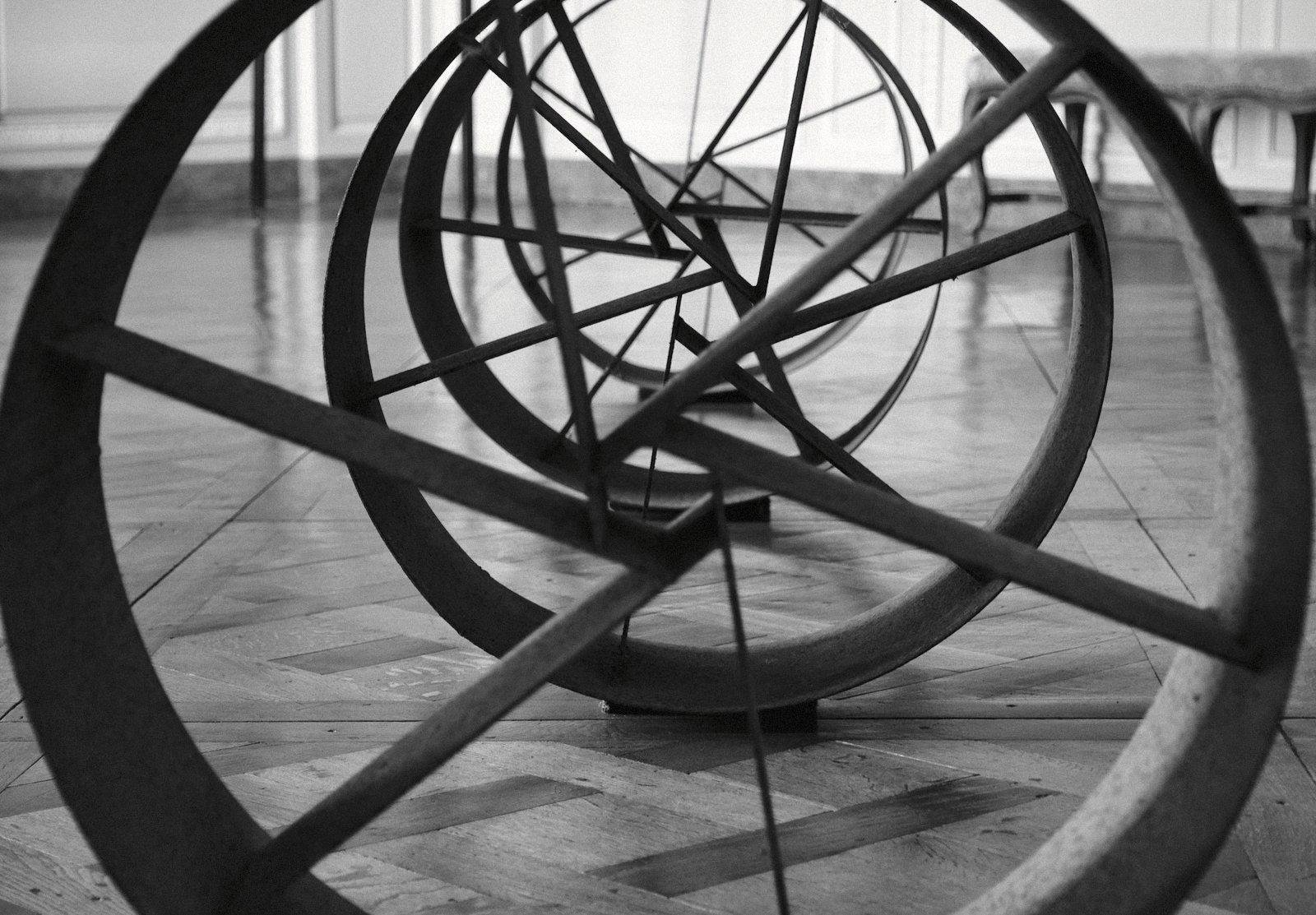 Photo format paysage en noir et blanc d’un alignement de cylindres métalliques avec des branche en leur intérieur qui forment une espèce de spirale