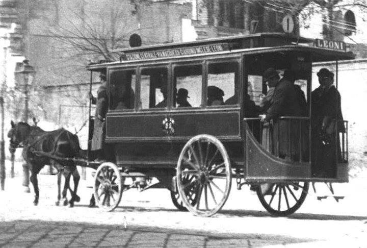 This image shows a horse-drawn tram from the past. It's an early public transportation vehicle with passengers inside. The tram is on rails and is being pulled by a horse, reflecting a common mode of transport before motorized vehicles became widespread.