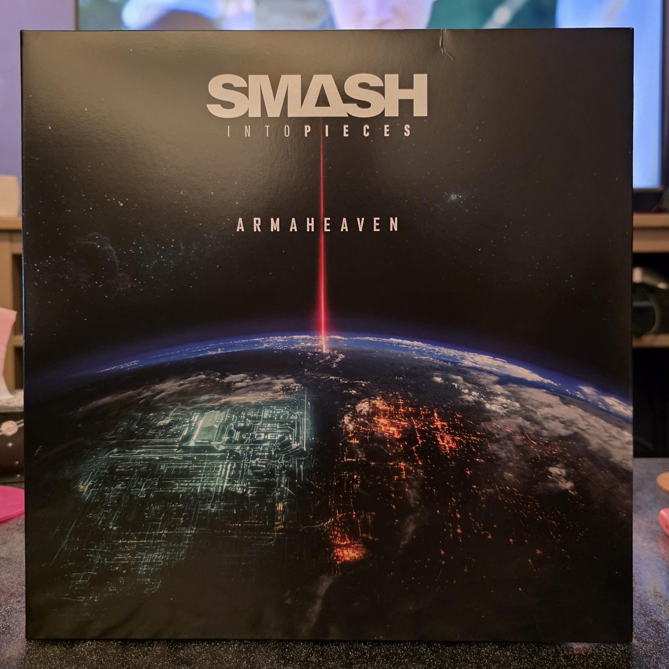 Front cover of the vinyl edition of Armaheaven, the latest album by Swedish alternative/electronic rock band Smash Into Pieces. The artwork shows Earth seen from space against a dark, star-filled background. A thin, bright red beam of light shoots vertically down from space to the planet’s surface, visually splitting the globe into two contrasting halves. On the left side, the surface looks cold and technological, with glowing circuit-like patterns in greenish tones. On the right side, the planet appears warmer and more chaotic, dotted with fiery orange city lights and glowing clusters. At the top, the band name “SMASH INTO PIECES” is printed in bold white letters, with the album title “ARMAHEAVEN” centered below it. The overall design feels cinematic and futuristic, reflecting the band’s signature mix of heavy guitars, electronic elements, and dramatic, emotional themes. Smash Into Pieces are known for their sci-fi inspired visuals, strong melodies, and the masked drummer APOC, and Armaheaven continues that dystopian, high-energy atmosphere both visually and musically.
