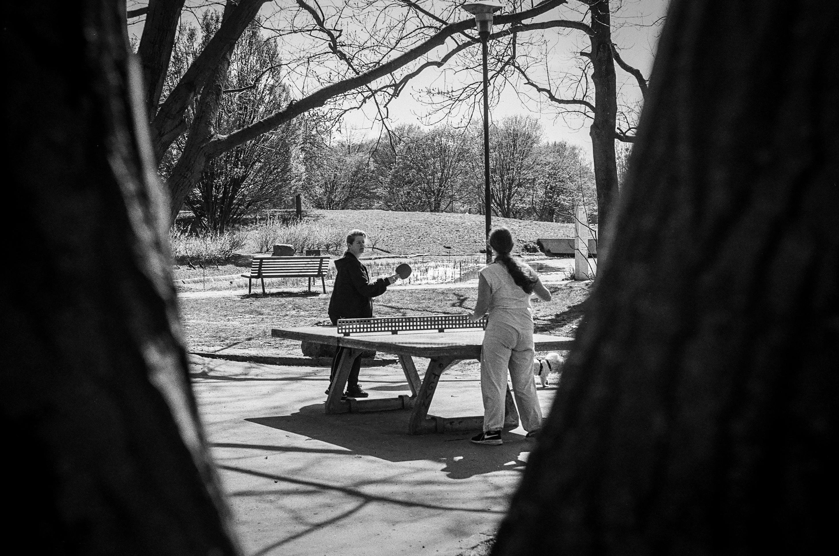 B&W photo of people playing ping-pong at a table in a park