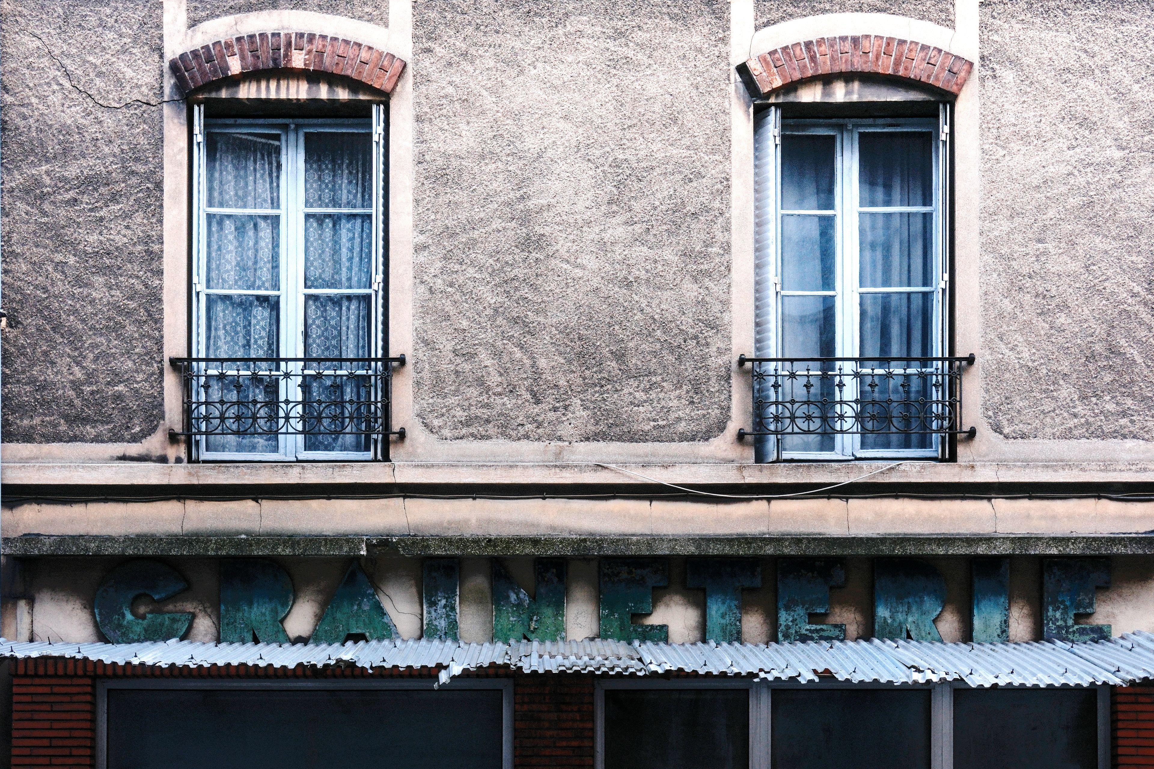 Photo horizontale. Une enseigne d’une vieille boutique désormais fermée où on peut lire «&nbsp;Graineterie&nbsp;» en majuscule dans une typo vintage. Au dessus, 2 fenêtres d’habitation