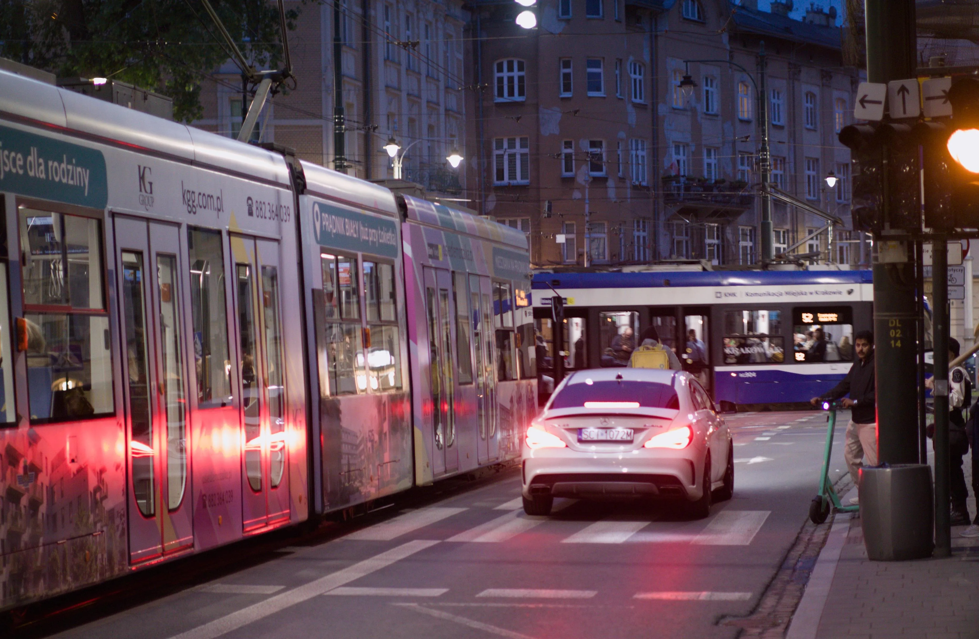 A photo of a busy cross-way with a car and two trams.