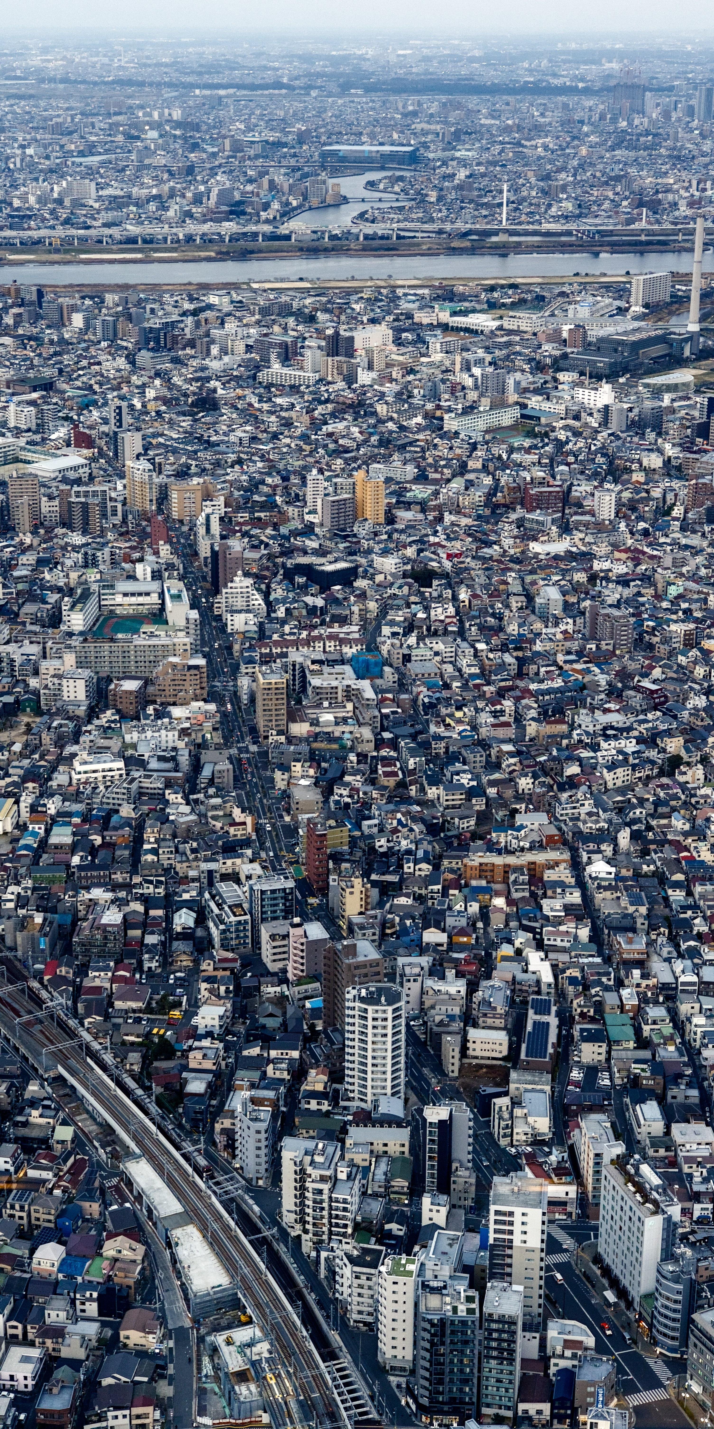 A view of Tokyo from the Skytree View Tower. The large amount of buildings and the urbanization span all across the vertical axis of the picture, up to the hazy horizon line at the top edge. The 2:1 vertical aspect ratio is used to emphasize the effect.