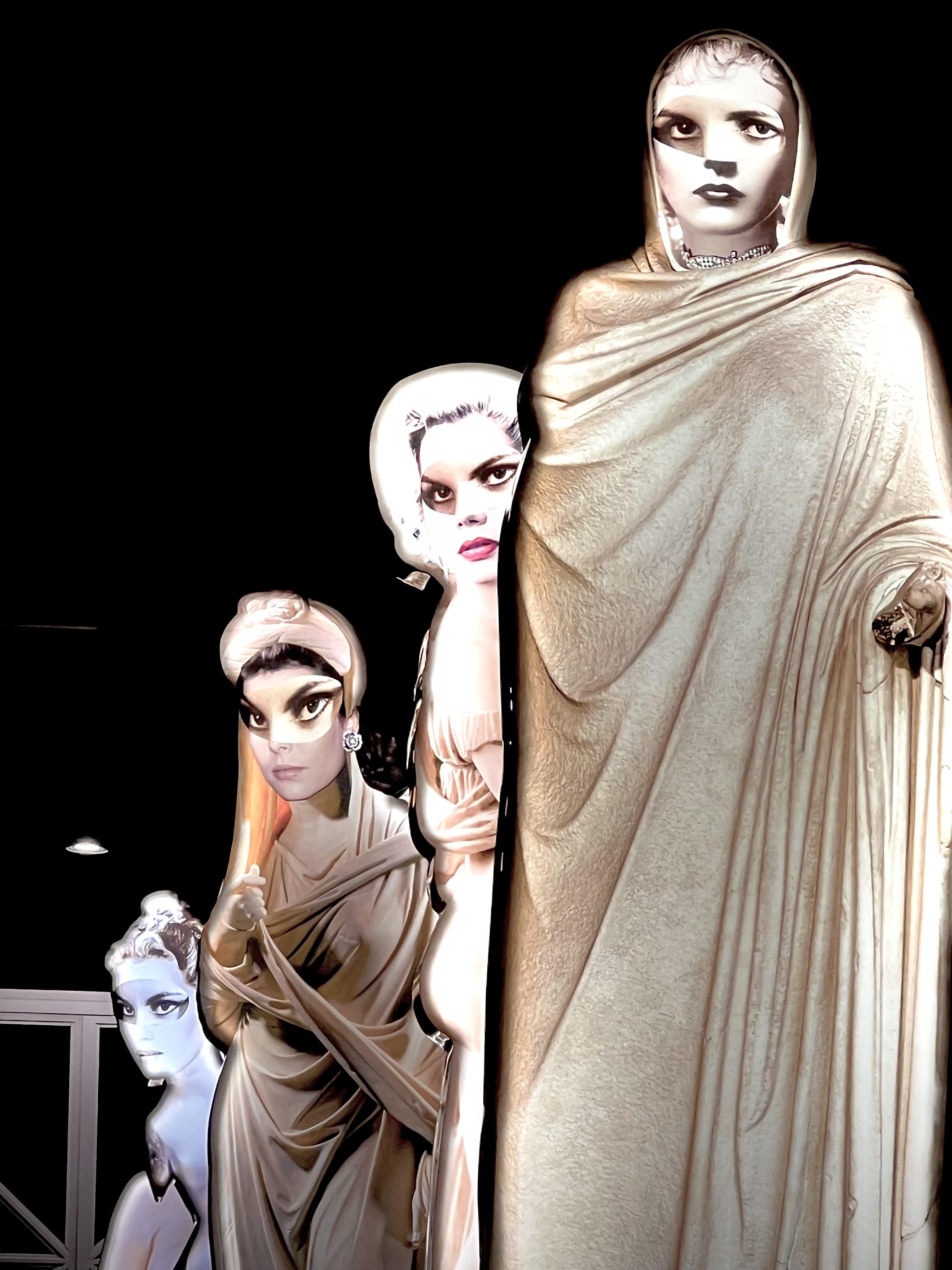 Statue con volti che sembrano essere digitalmente o artisticamente migliorati. Le figure sono vestite con drappeggi in stile classico. I tratti facciali migliorati conferiscono loro un aspetto surreale o artistico moderno, ambientato su uno sfondo scuro.