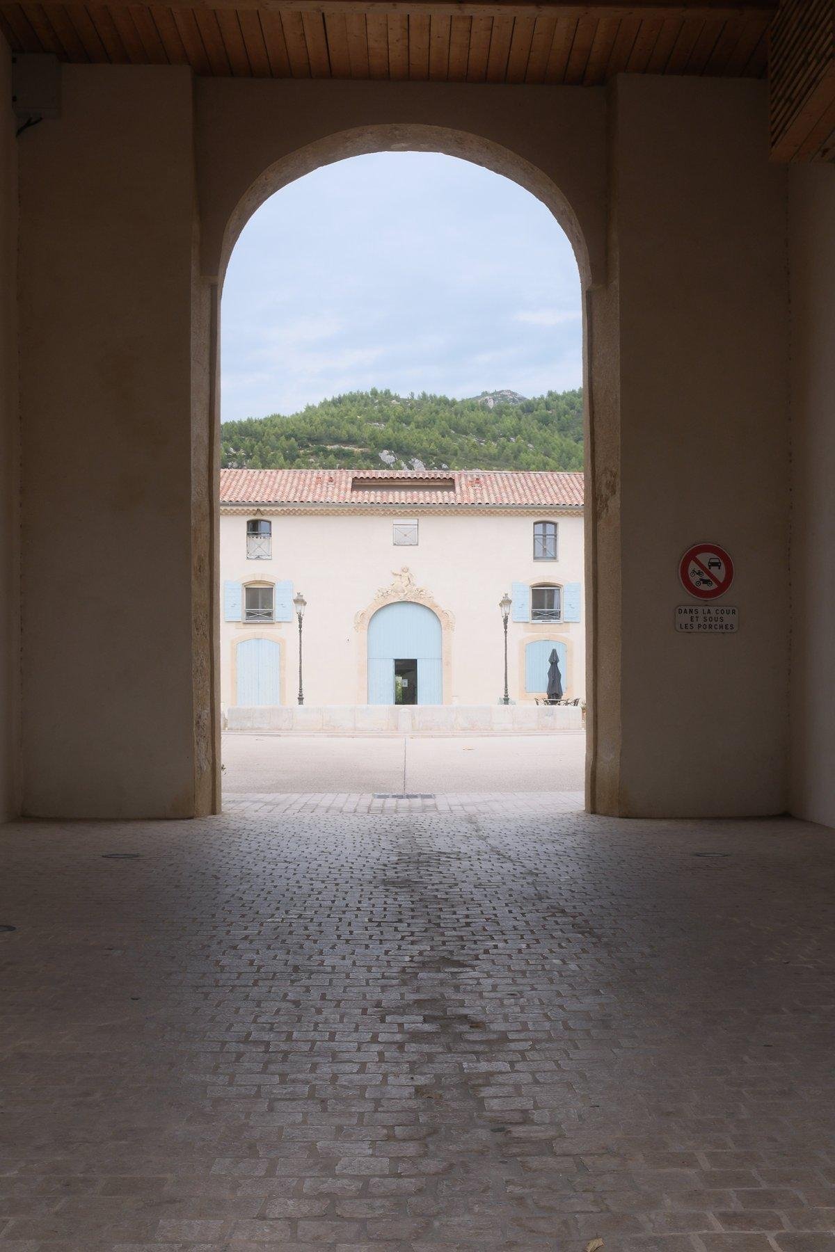 Photo verticale. Un porche menant à une grande cours piétonne